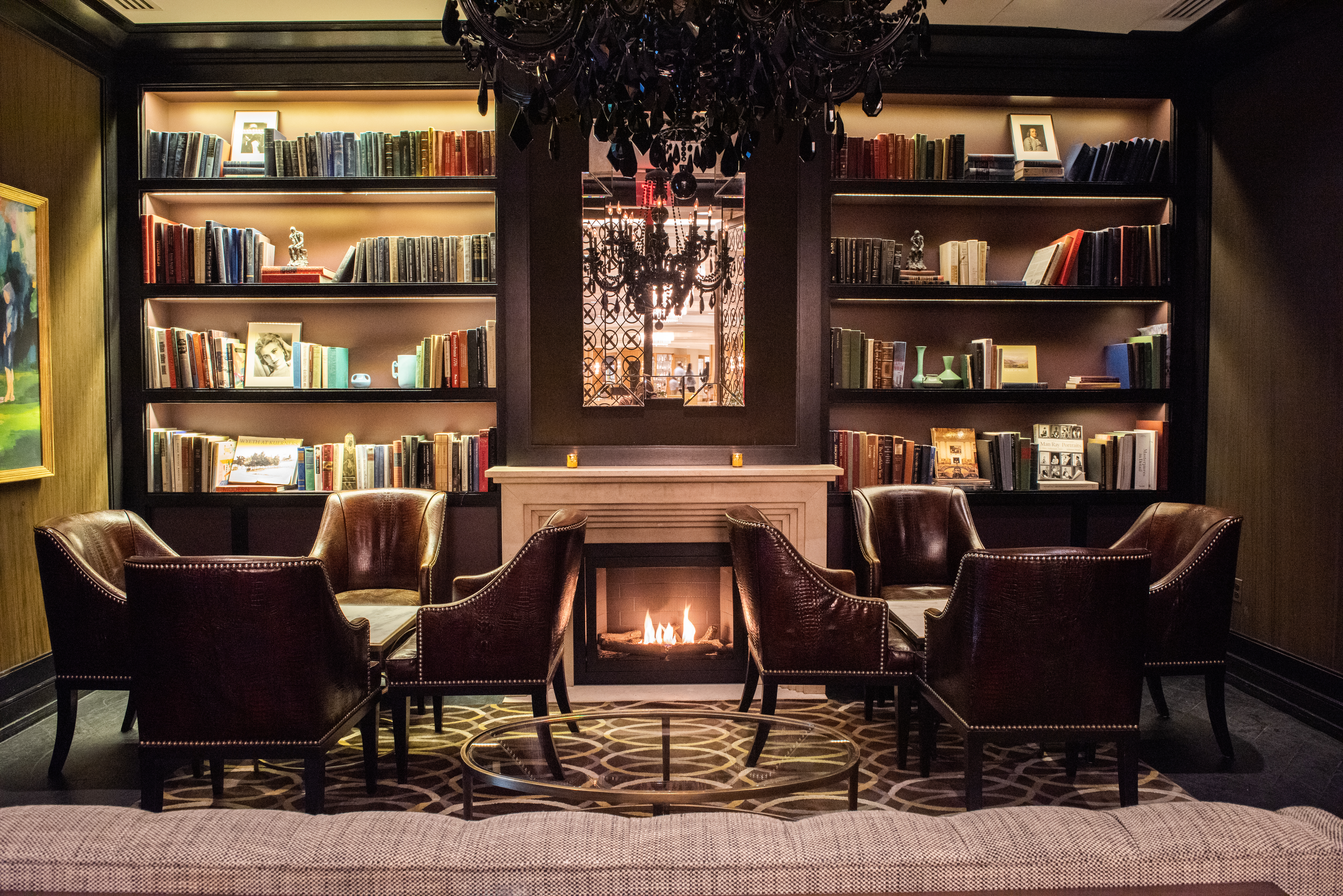 library with leather chairs and lit fireplace