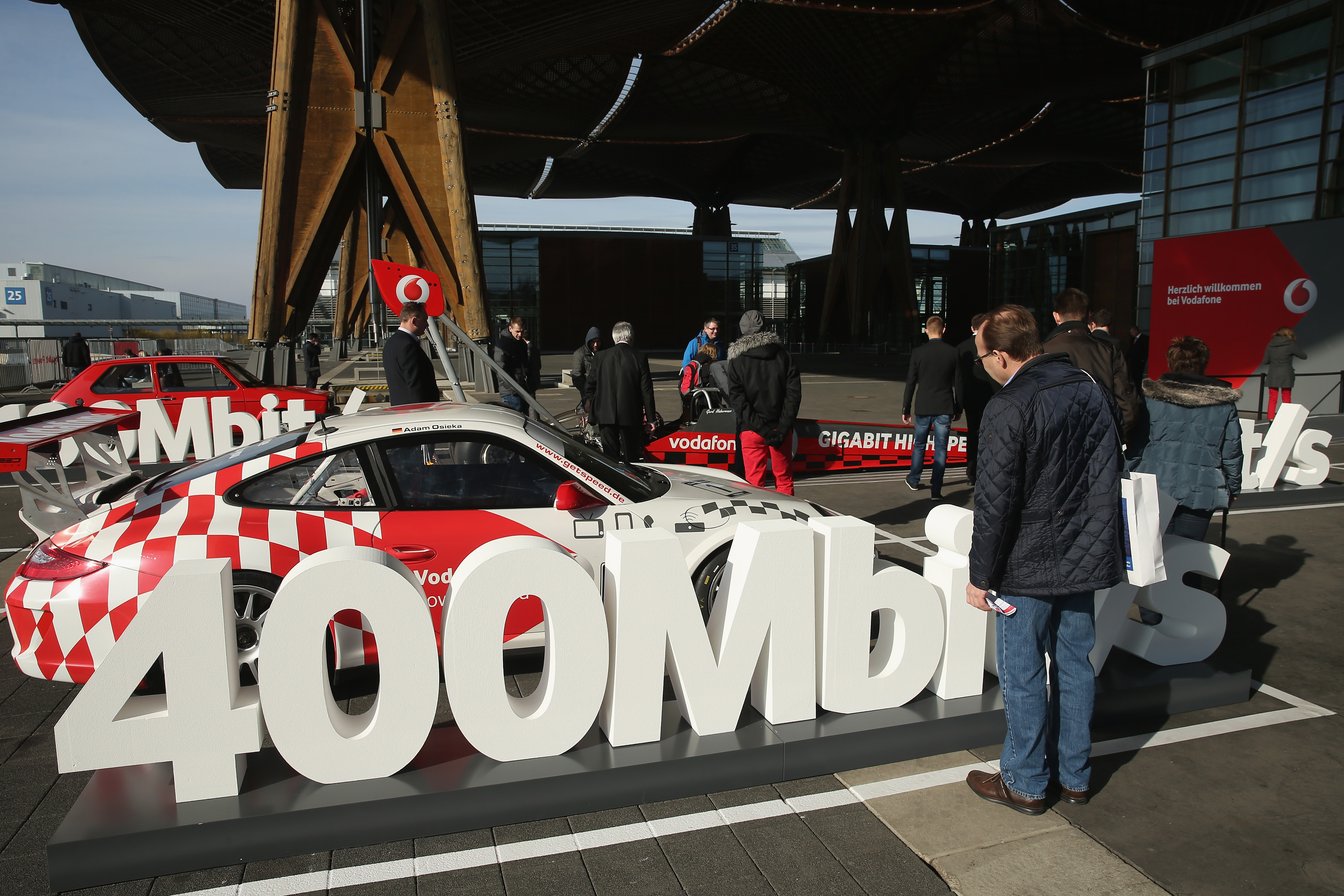 &nbsp;A visitor looks at a Porsche car meant to represent the speed of a 400 Mbit/s Internet connection outside the Vodafone stan