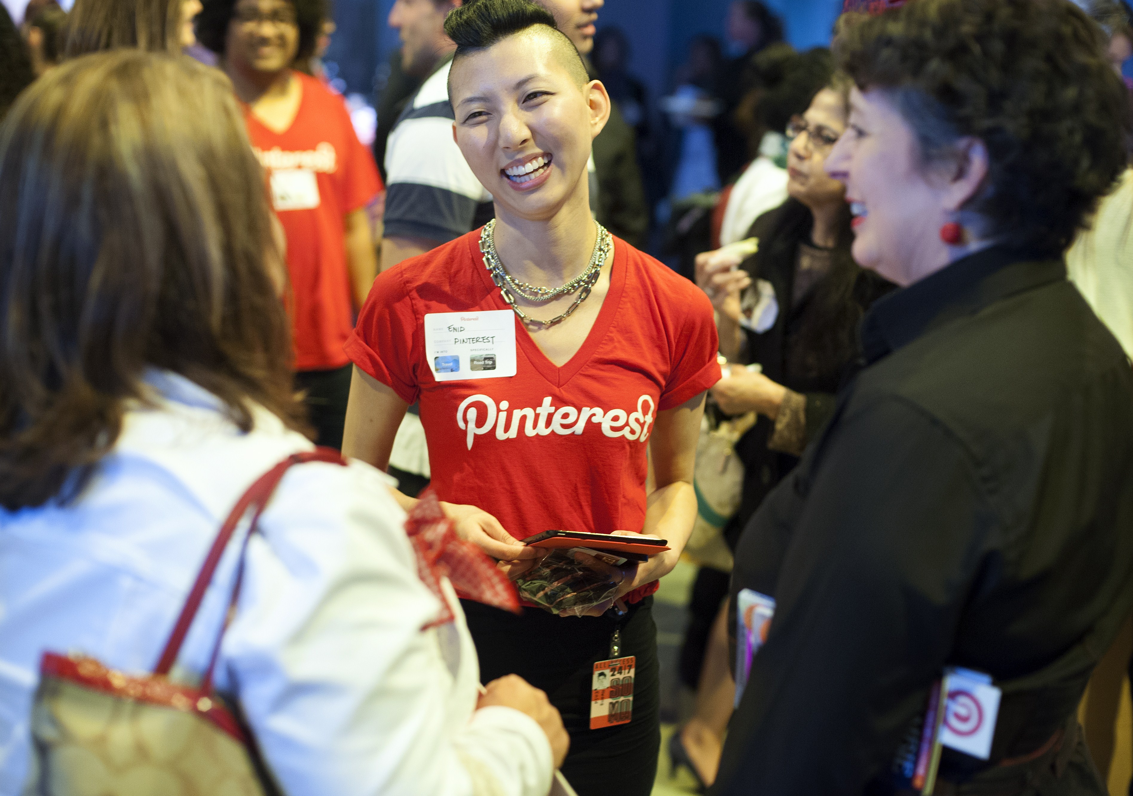 A Pinterest employee in a red Pinterest shirt welcomes guests to the company headquarters for an event.