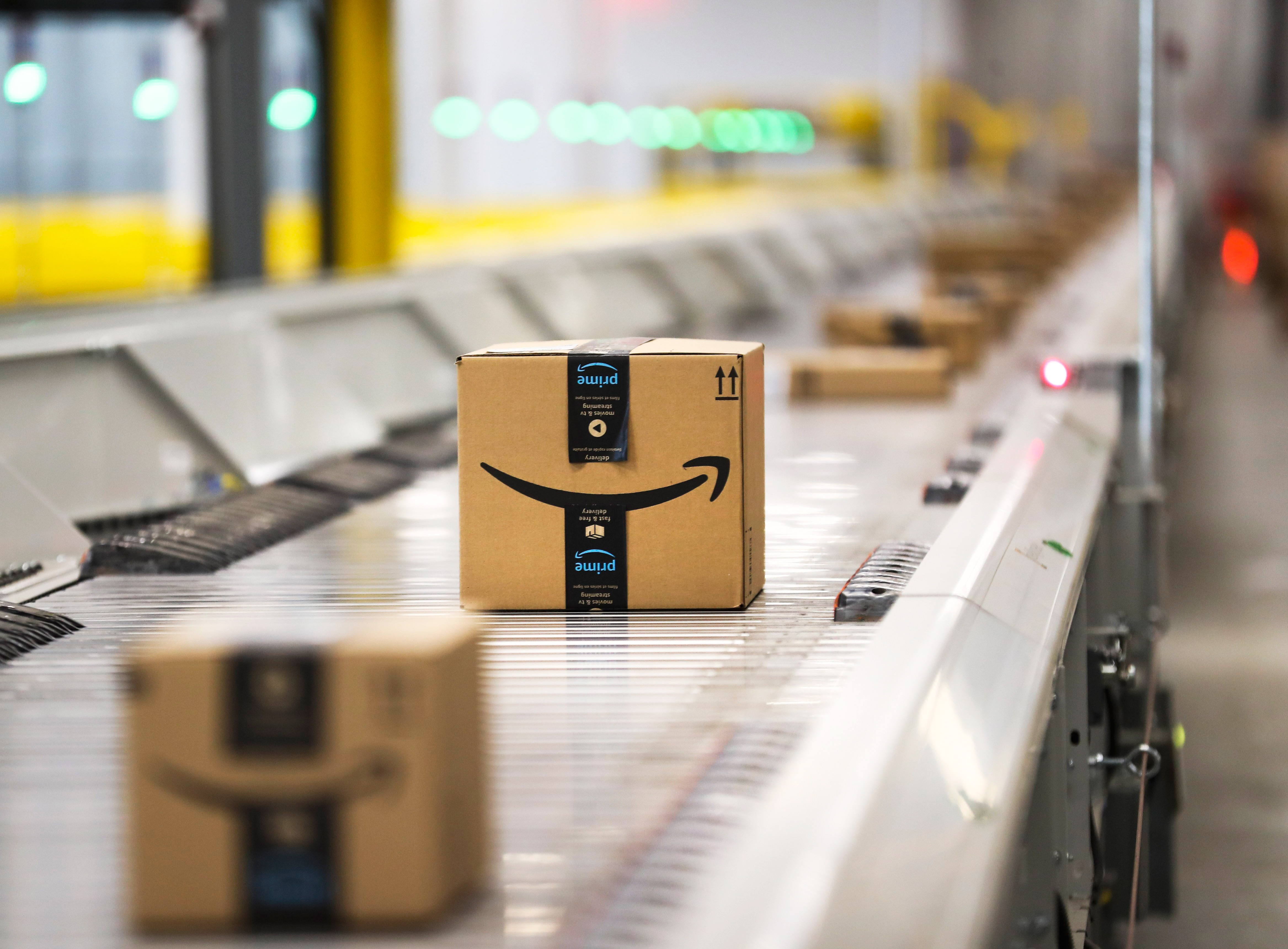 Amazon-branded shipping boxes go down a conveyor belt.