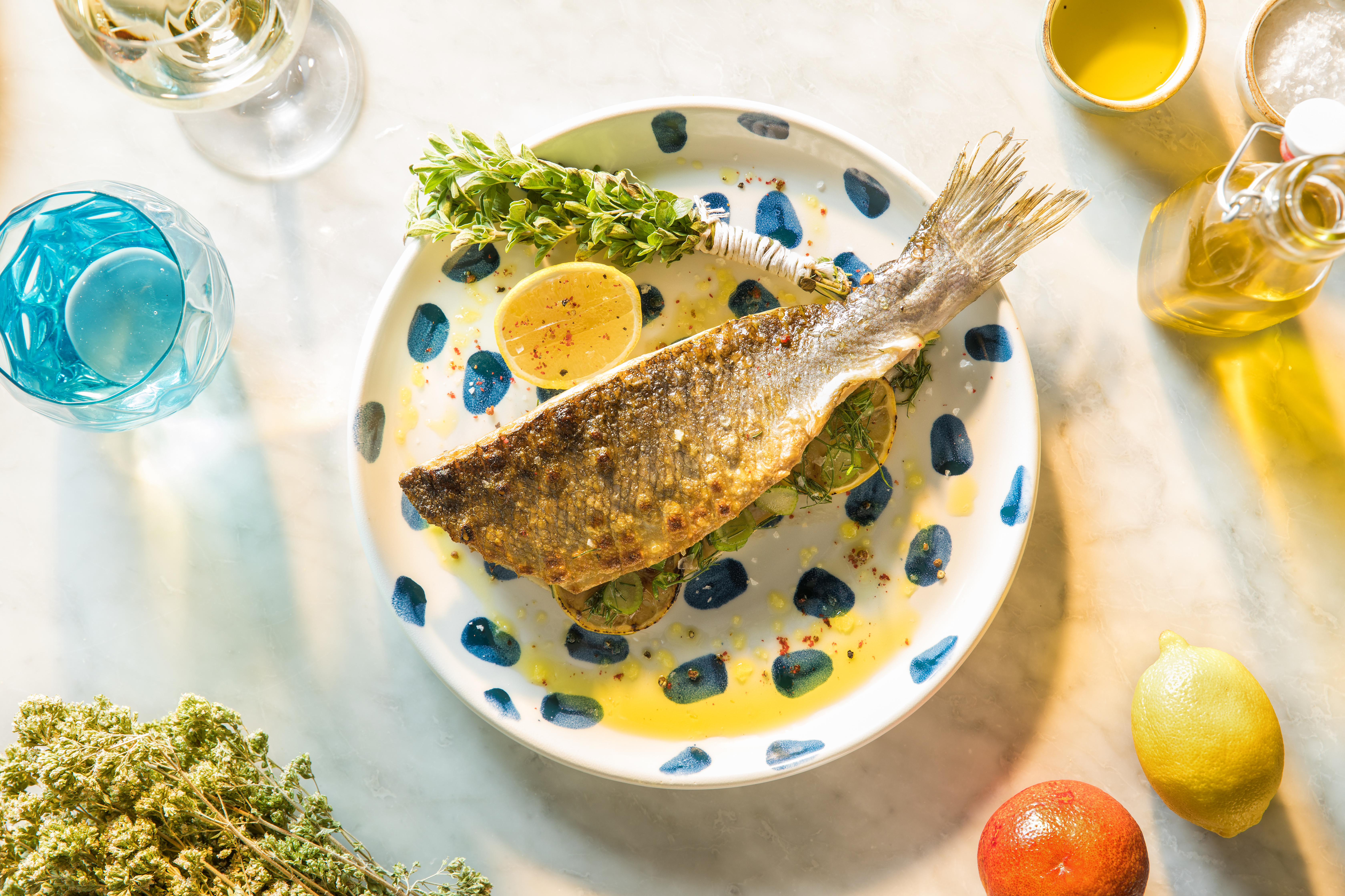Grilled branzino on a white plate with blue spots