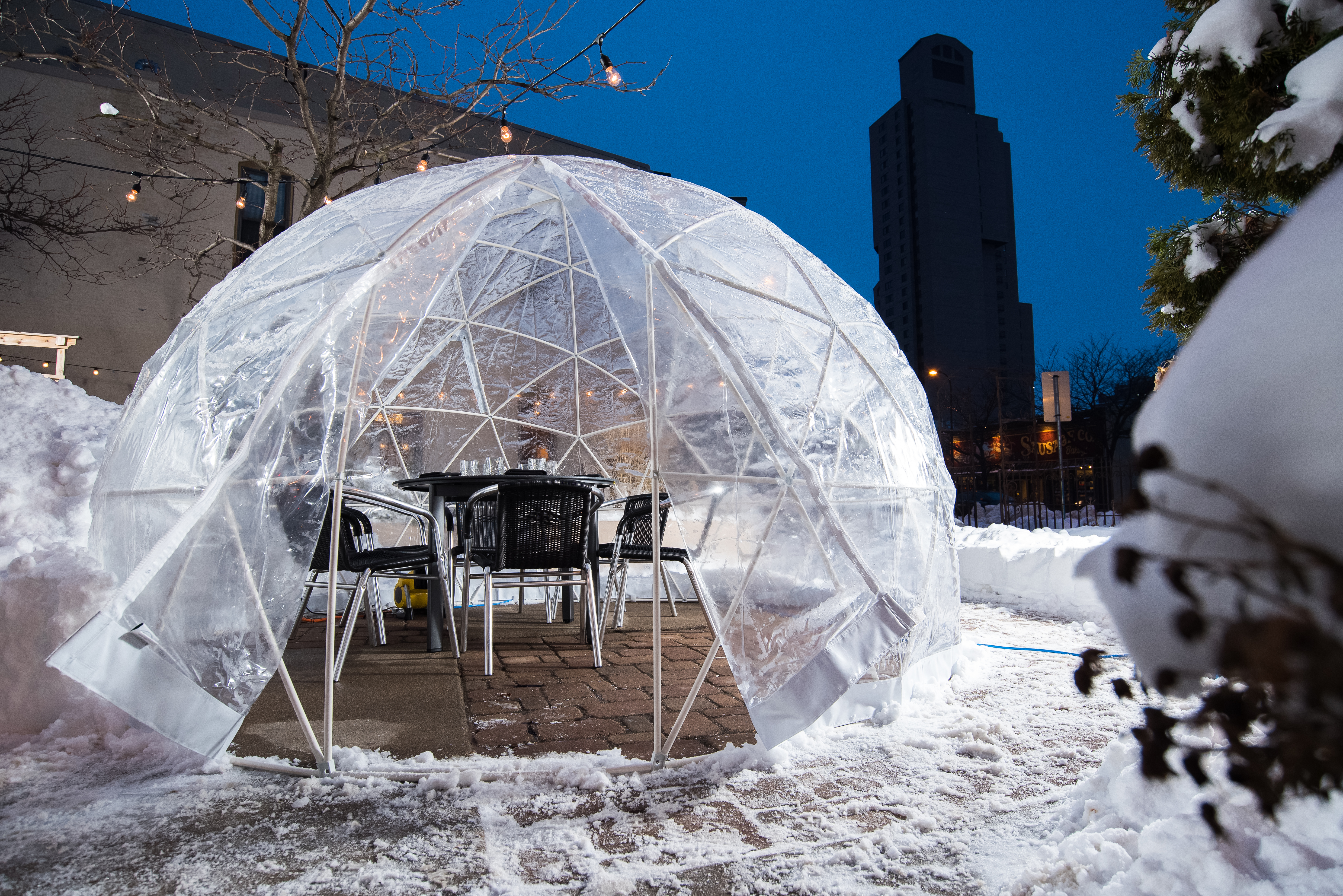 A plastic dome with a table set, surrounded by snow