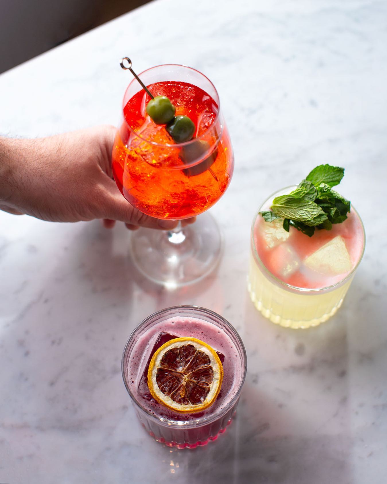 three cocktails topped with fruit
