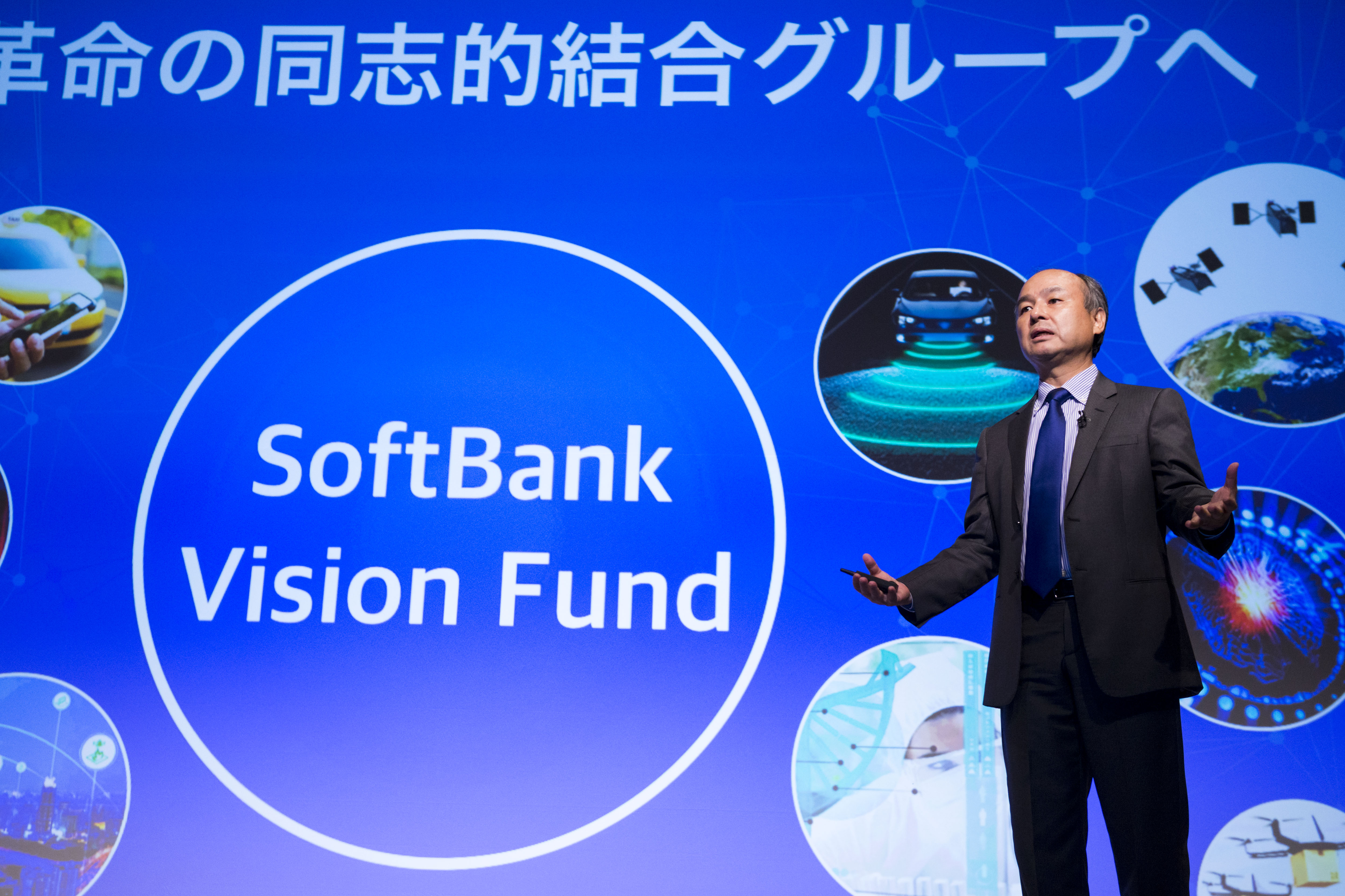 SoftBank Group CEO Masayoshi Son onstage in front of a backdrop in Japanese and English that reads “SoftBank Vision Fund.”