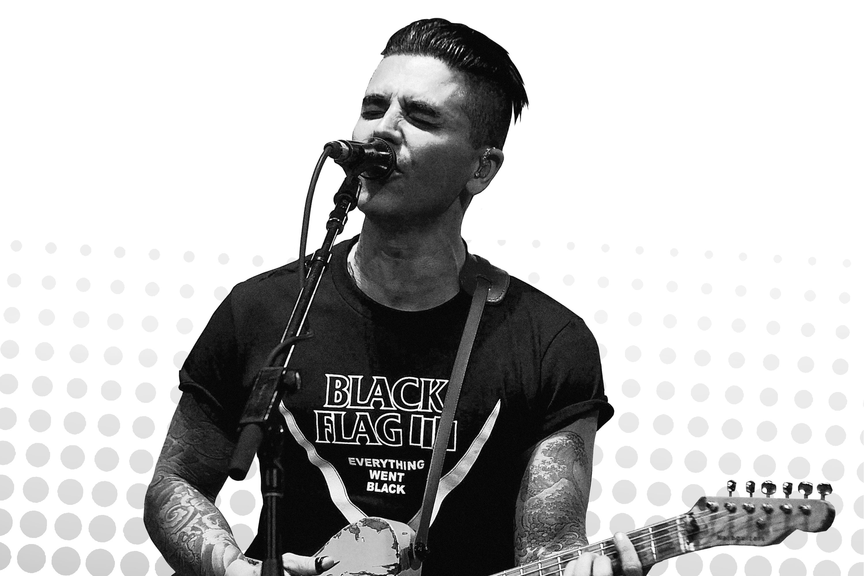 A black-and-white picture of Chris Carrabba playing guitar and singing