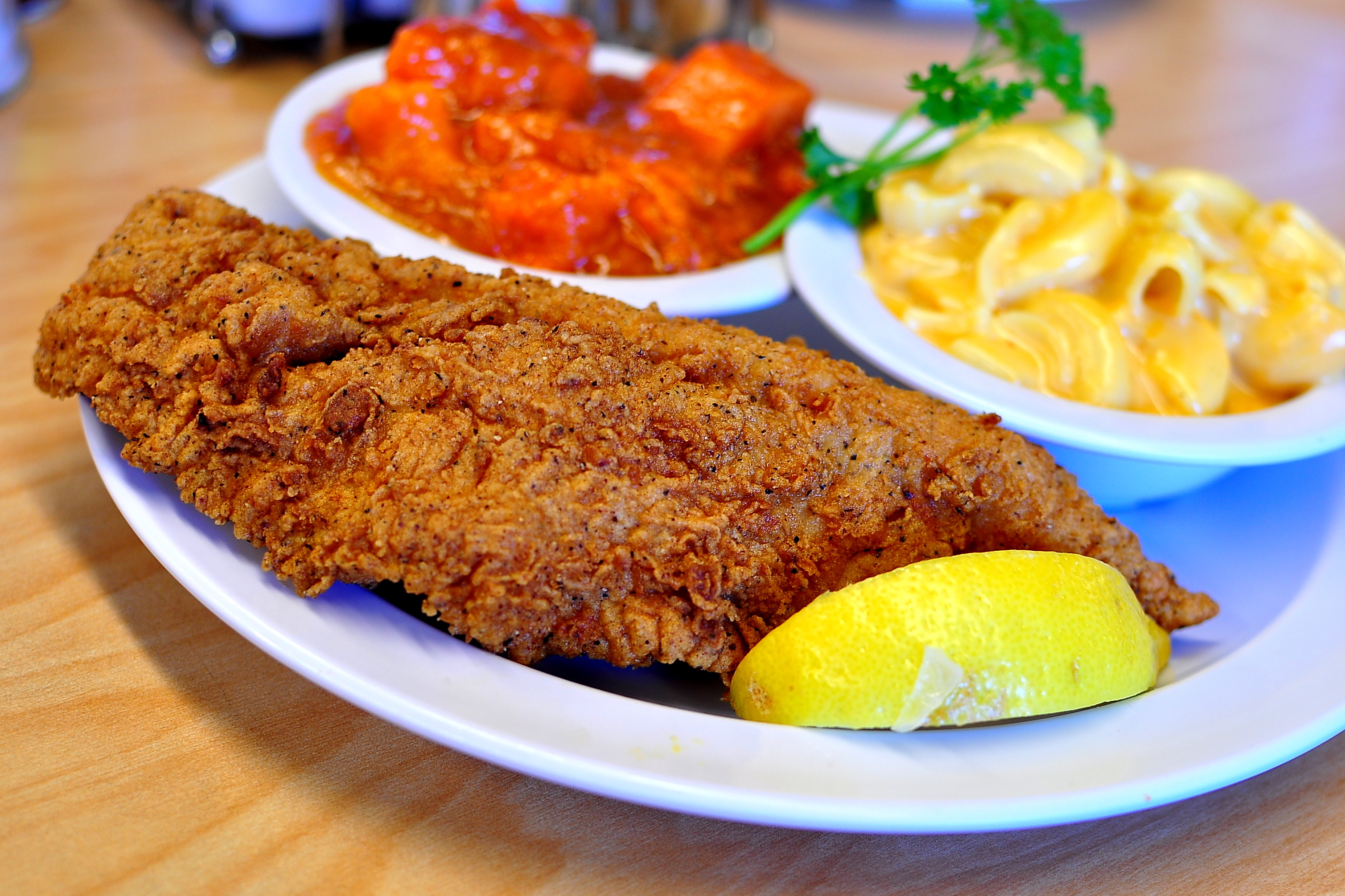 A platter of fried fish from Serving Spoon in Inglewood, California on a wooden table.