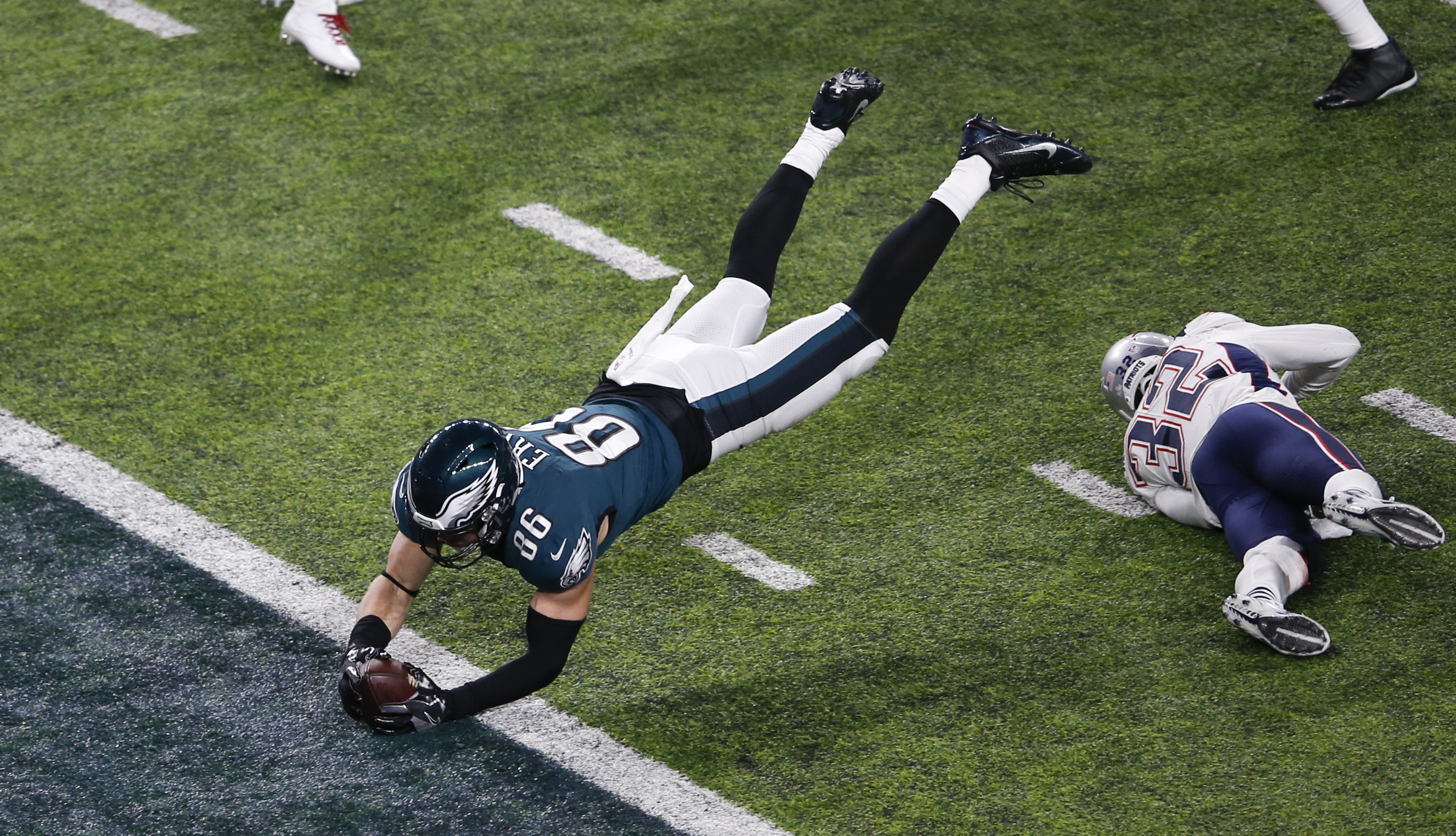 A Philadelphia Eagles football player scores a touchdown by leaping football-first into the end zone.