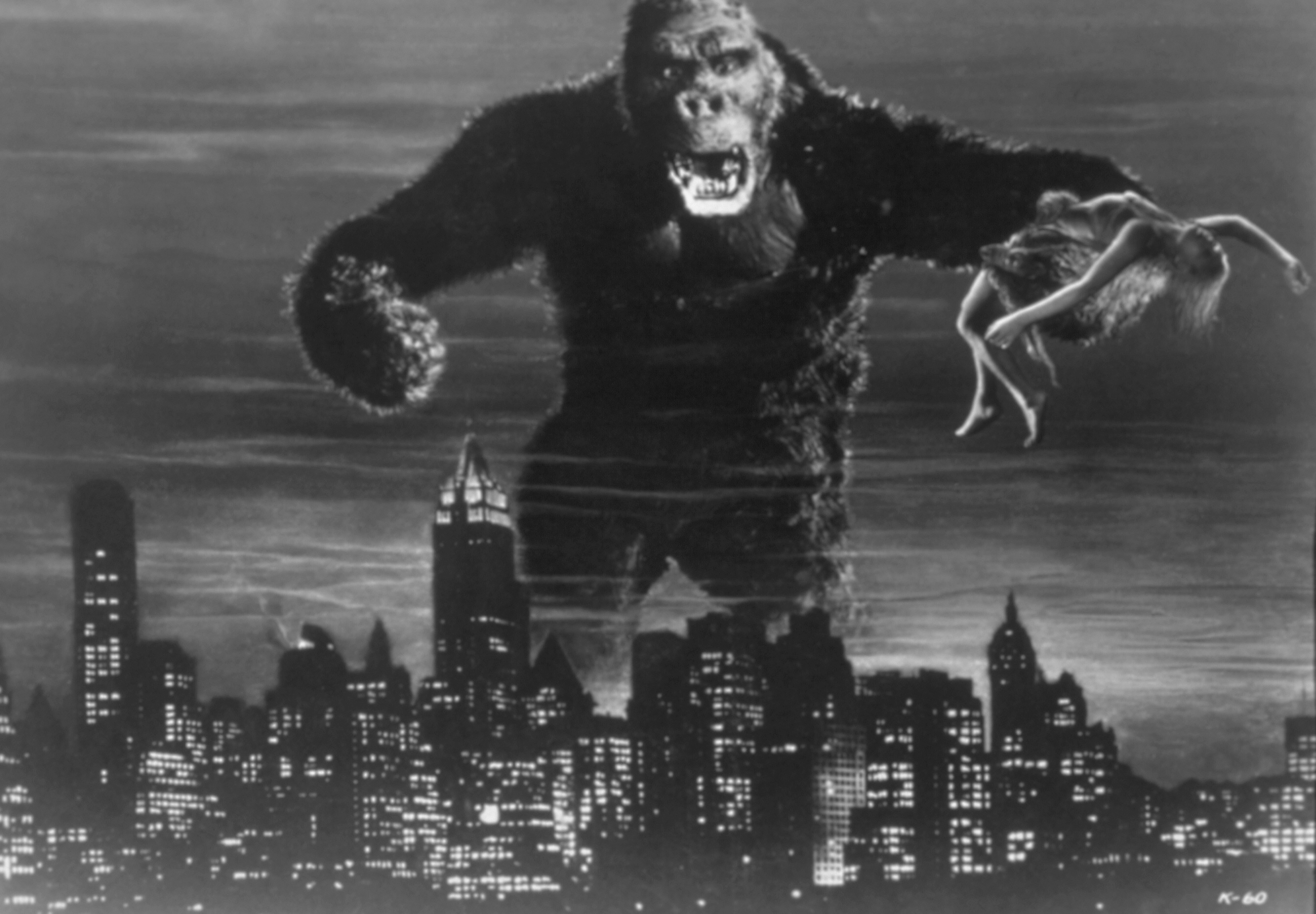 A movie still from “King Kong” showing the ape holding a woman and rampaging across a city skyline