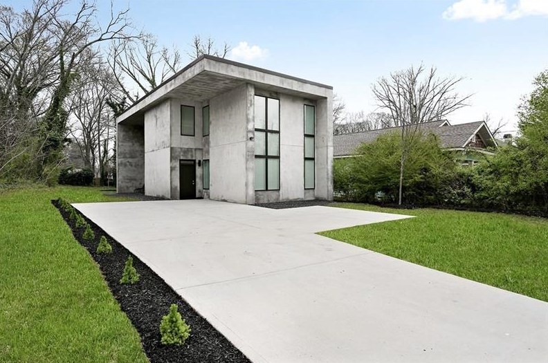 Two-story concrete house with long driveway.