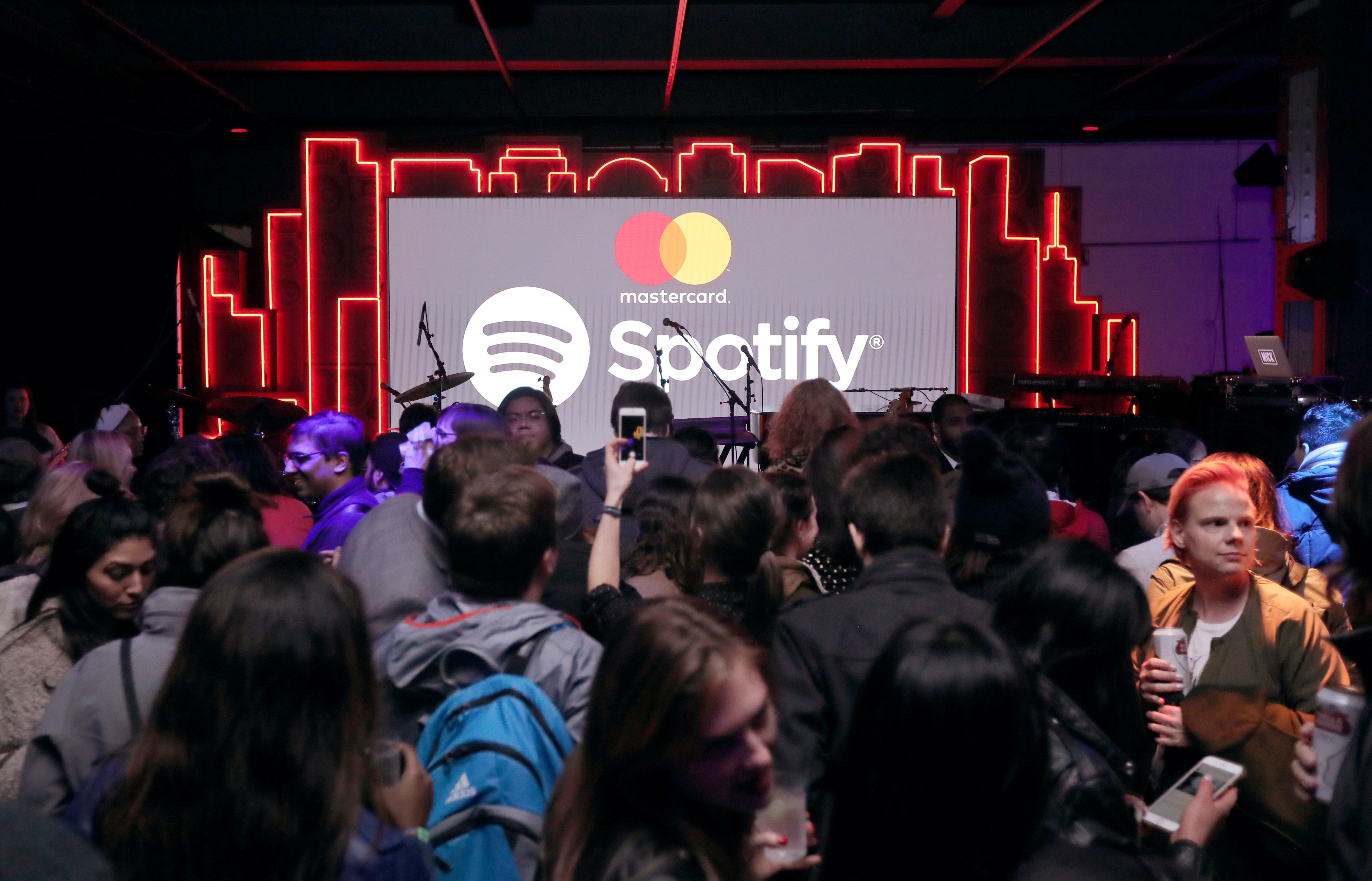 A crowd of people around a stage at a Spotify event co-sponsored by Mastercard