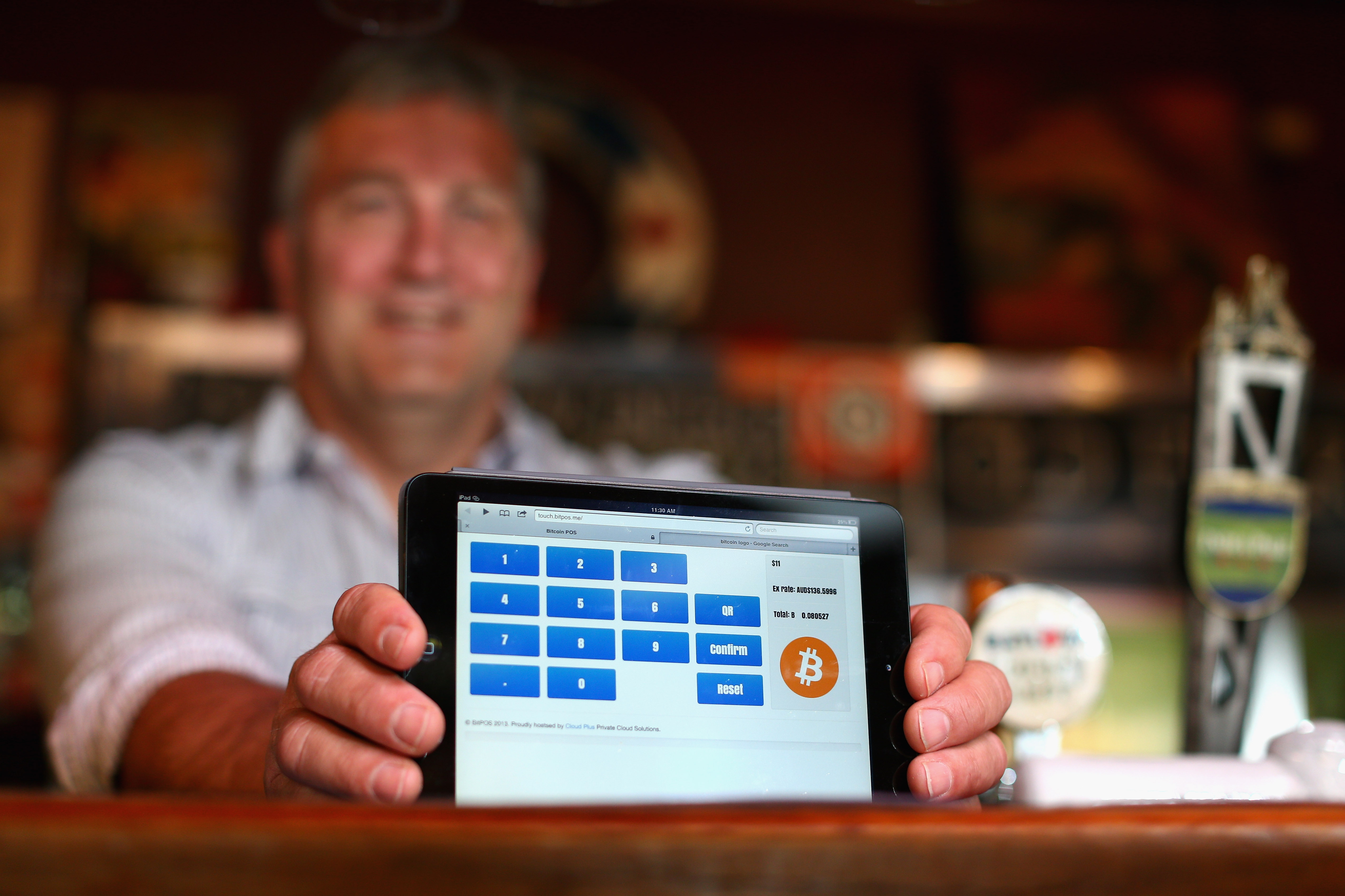 A barman at a Sydney pub shows a tablet screen that accepts bitcoin as payment for drinks.