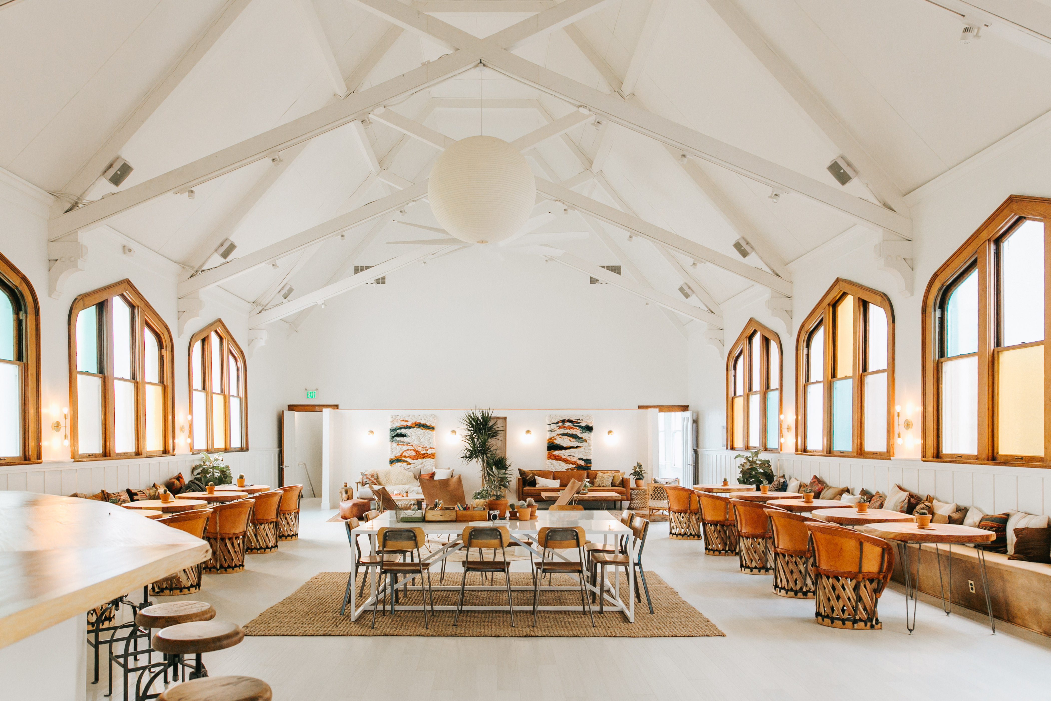 The interior of the co-working space The Assembly in San Francisco’s Mission District. There are multiple chairs and tables. The ceilings are high with white structural beams. There are multiple windows.