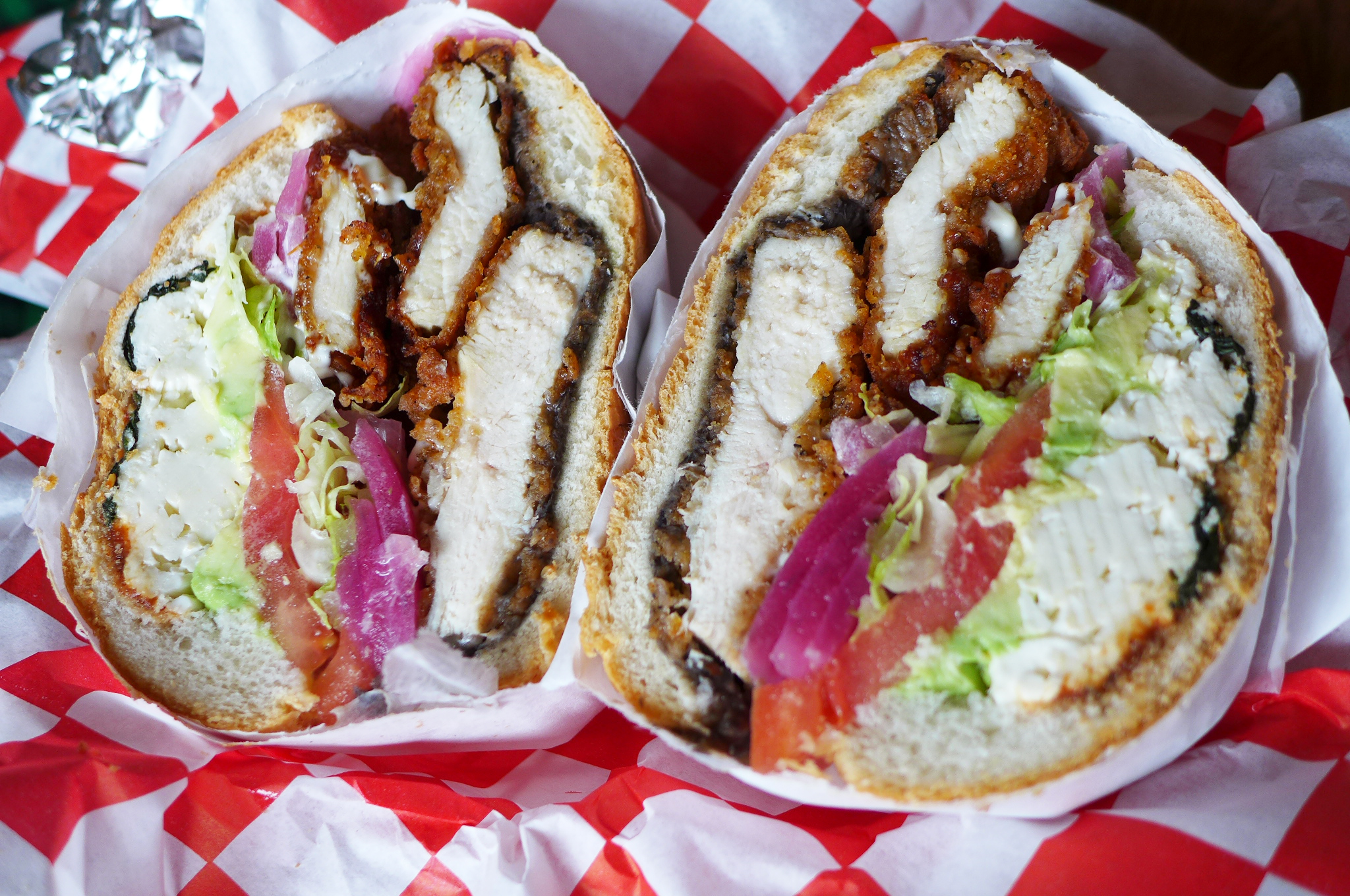 A Mexican cemita sandwich loaded with fried chicken seen in cross section.