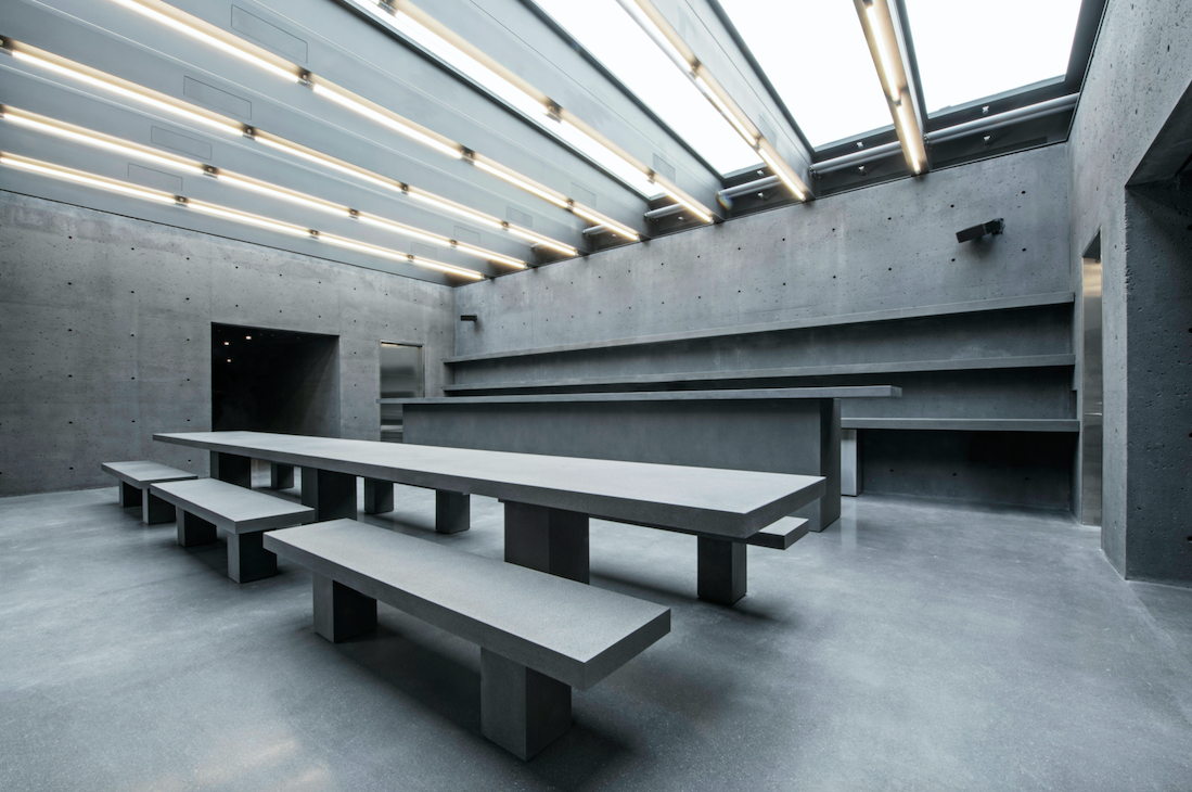 A concrete room with fluorescent lights and concrete tables.