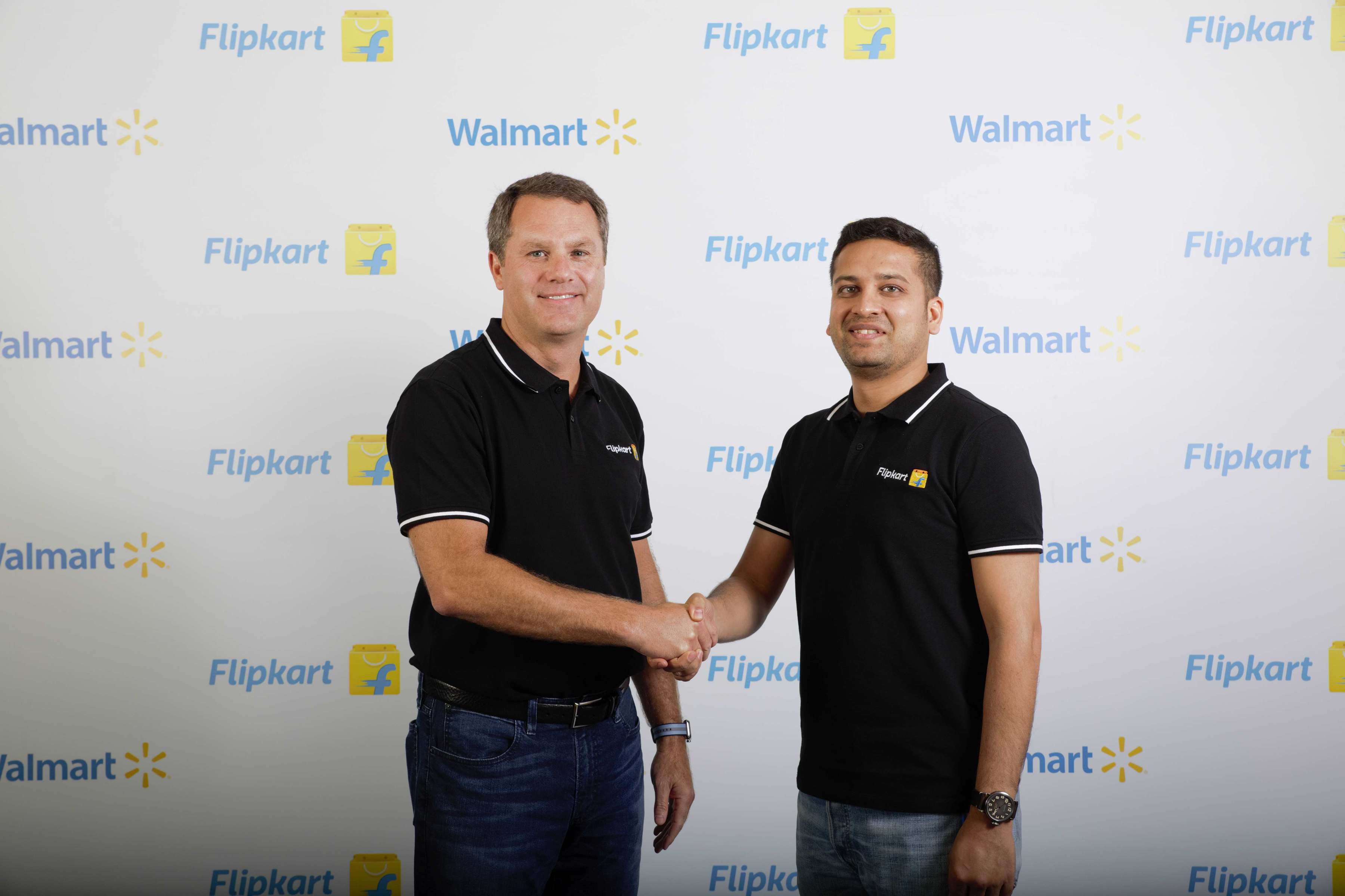 Walmart CEO Doug McMillon shakes hands and poses with Flipkart co-founder Binny Bansal