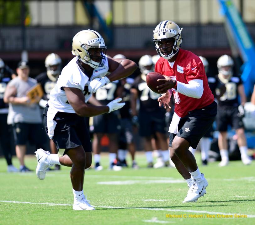 METAIRIE, LA - New Orleans Saints quarterback J.T. Barrett (5) rehearses a handoff to tryout running back Josh Rounds (24) during rookie minicamp practices at the Ochsner Sports Performance Center.