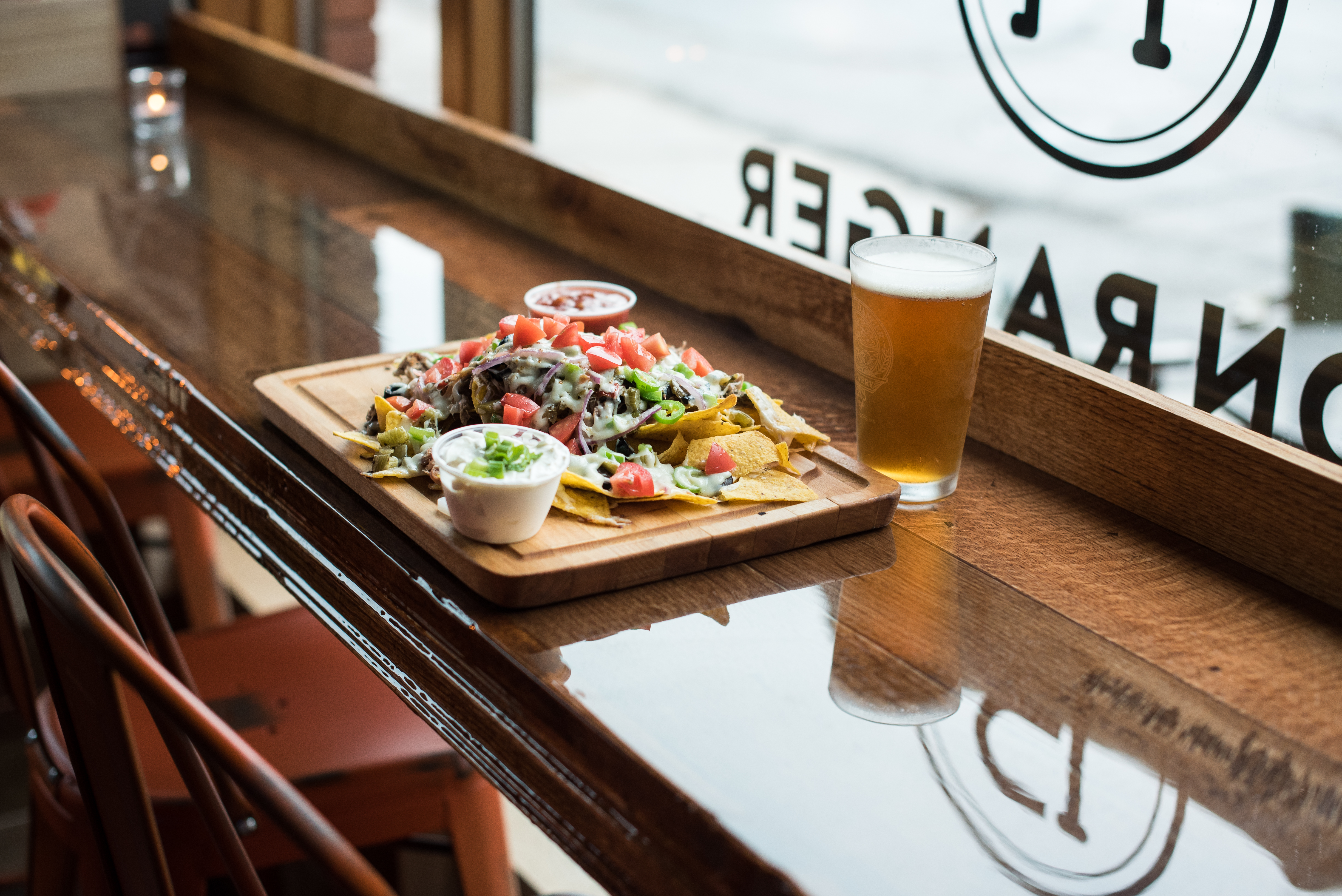 Facing the Iron Ranger’s front window is a cutting board loaded with nachos next to a pint of beer