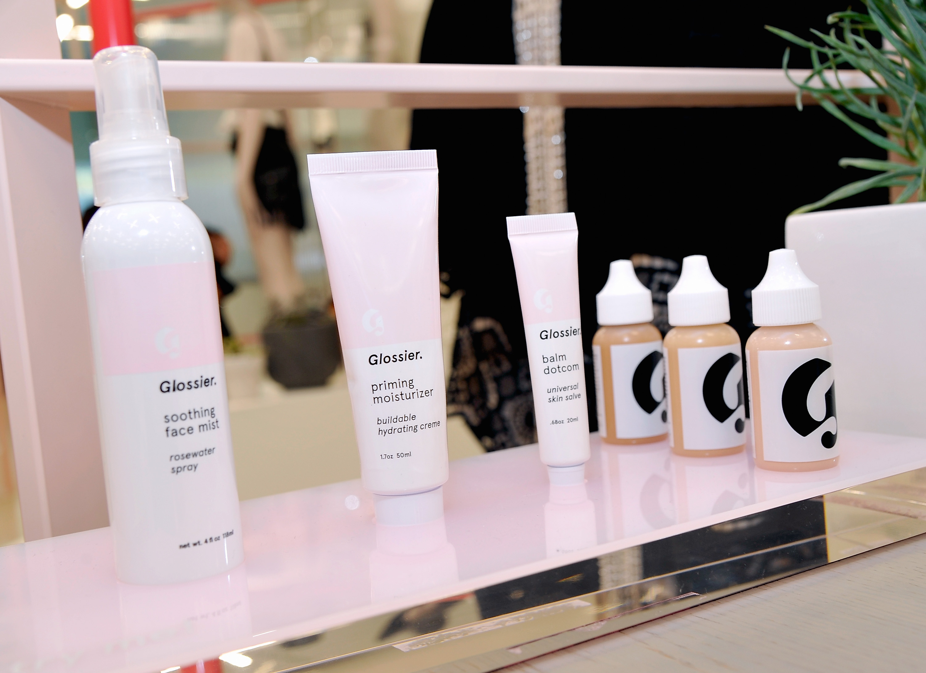 Bottles of Glossier products lined up on a shelf