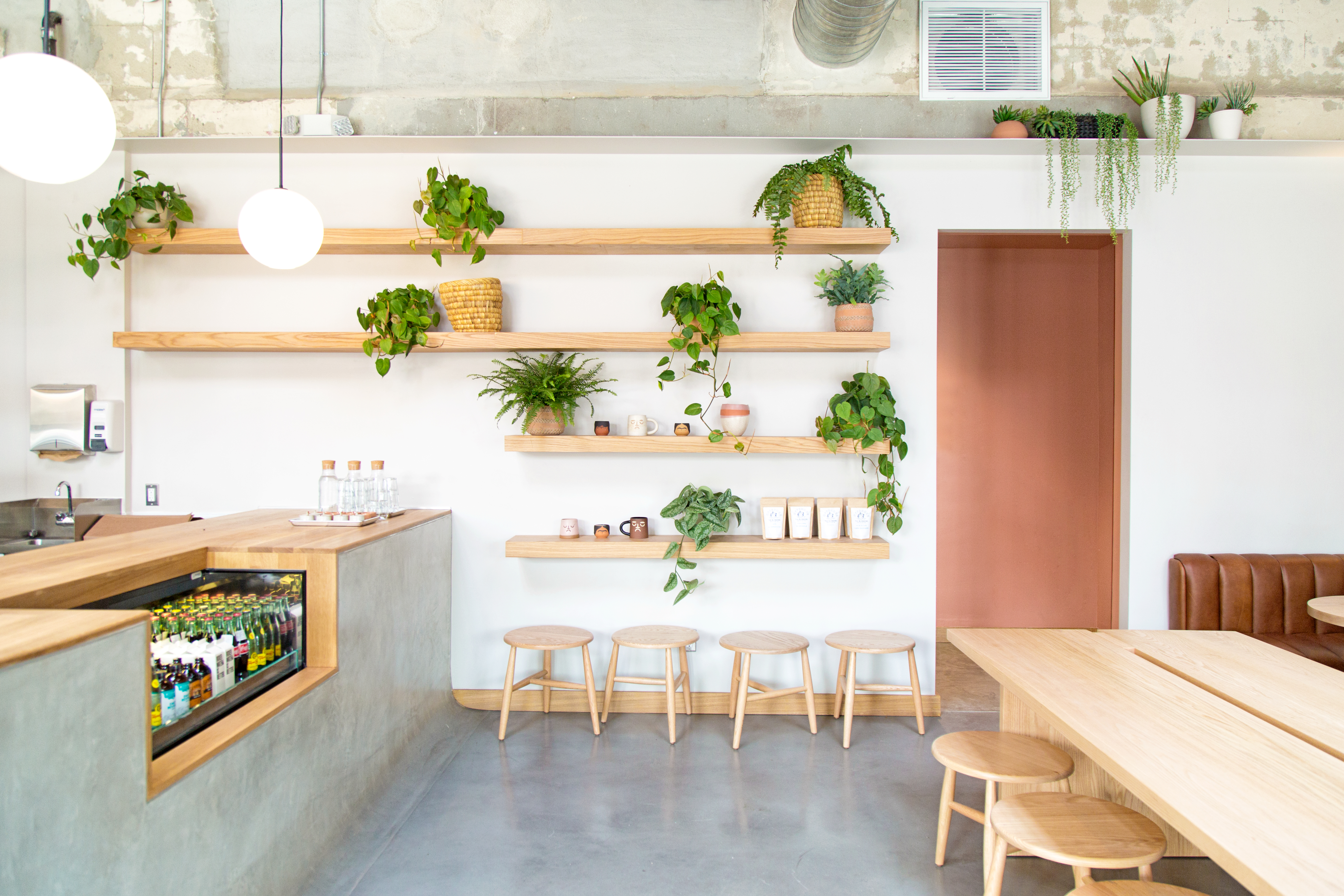 A bright room with wood tables, plants, and chairs at Highly Likely Cafe in Los Angeles, California.