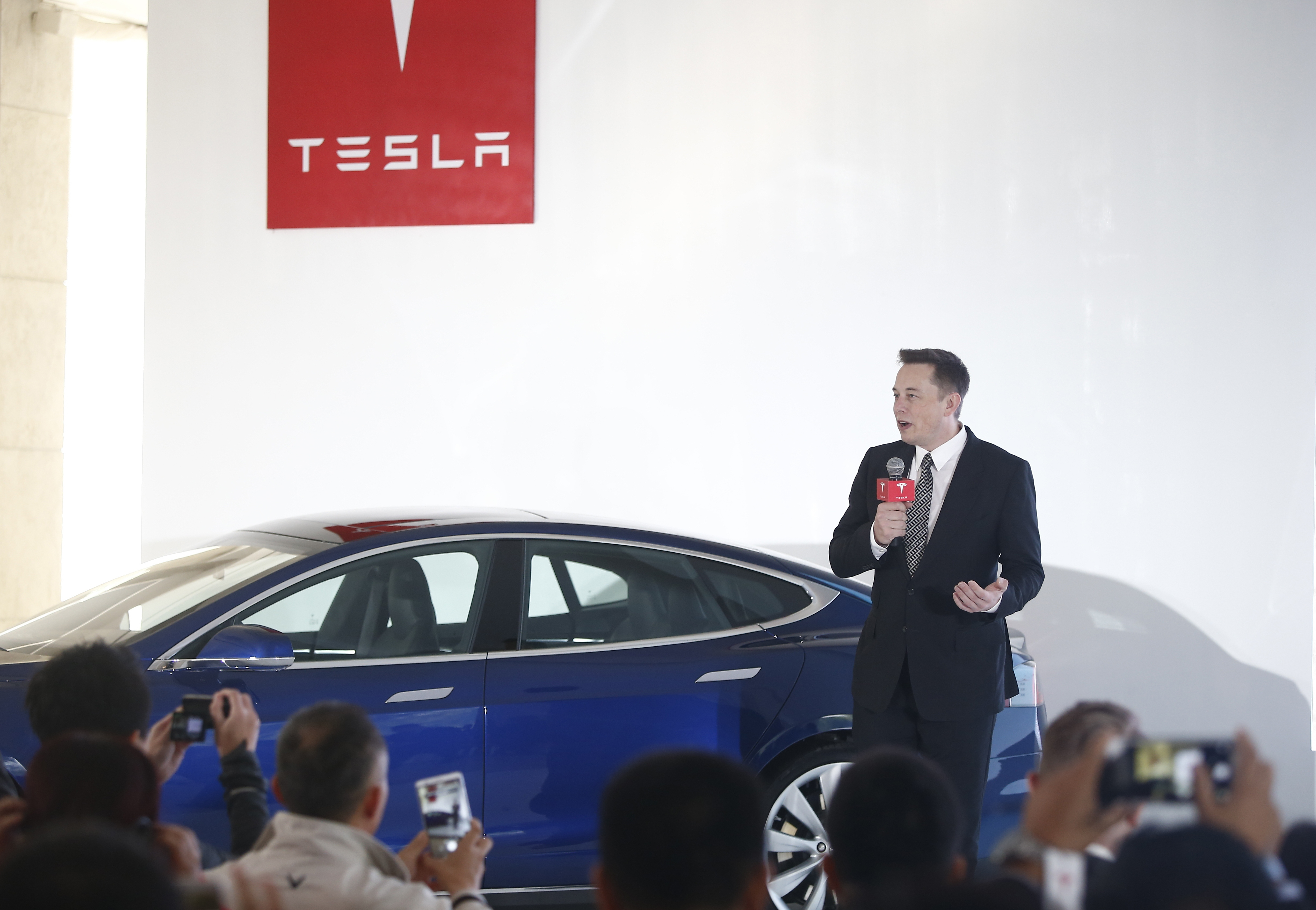 Tesla CEO Elon Musk onstage with a Tesla car