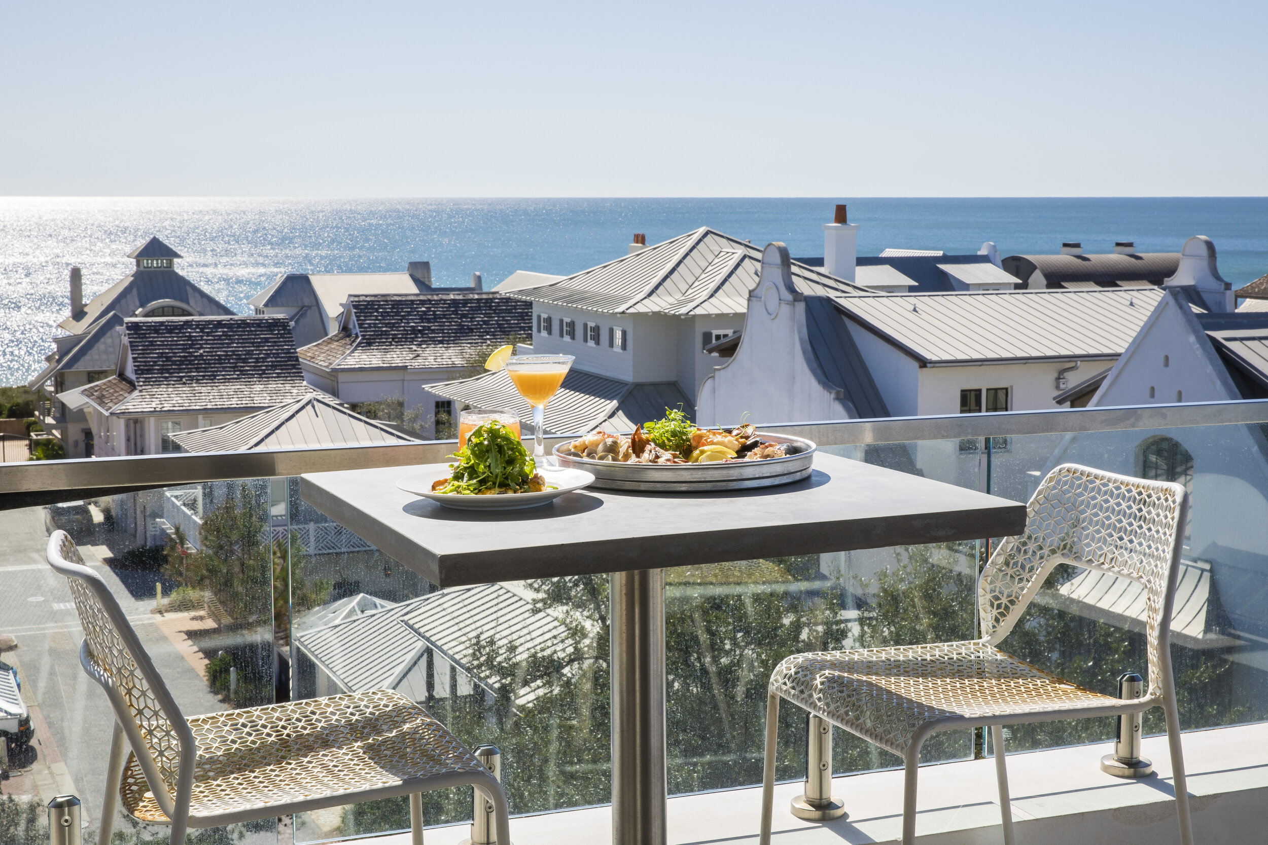 A rooftop table overlooks houses and beyond them, the Gulf Coast.