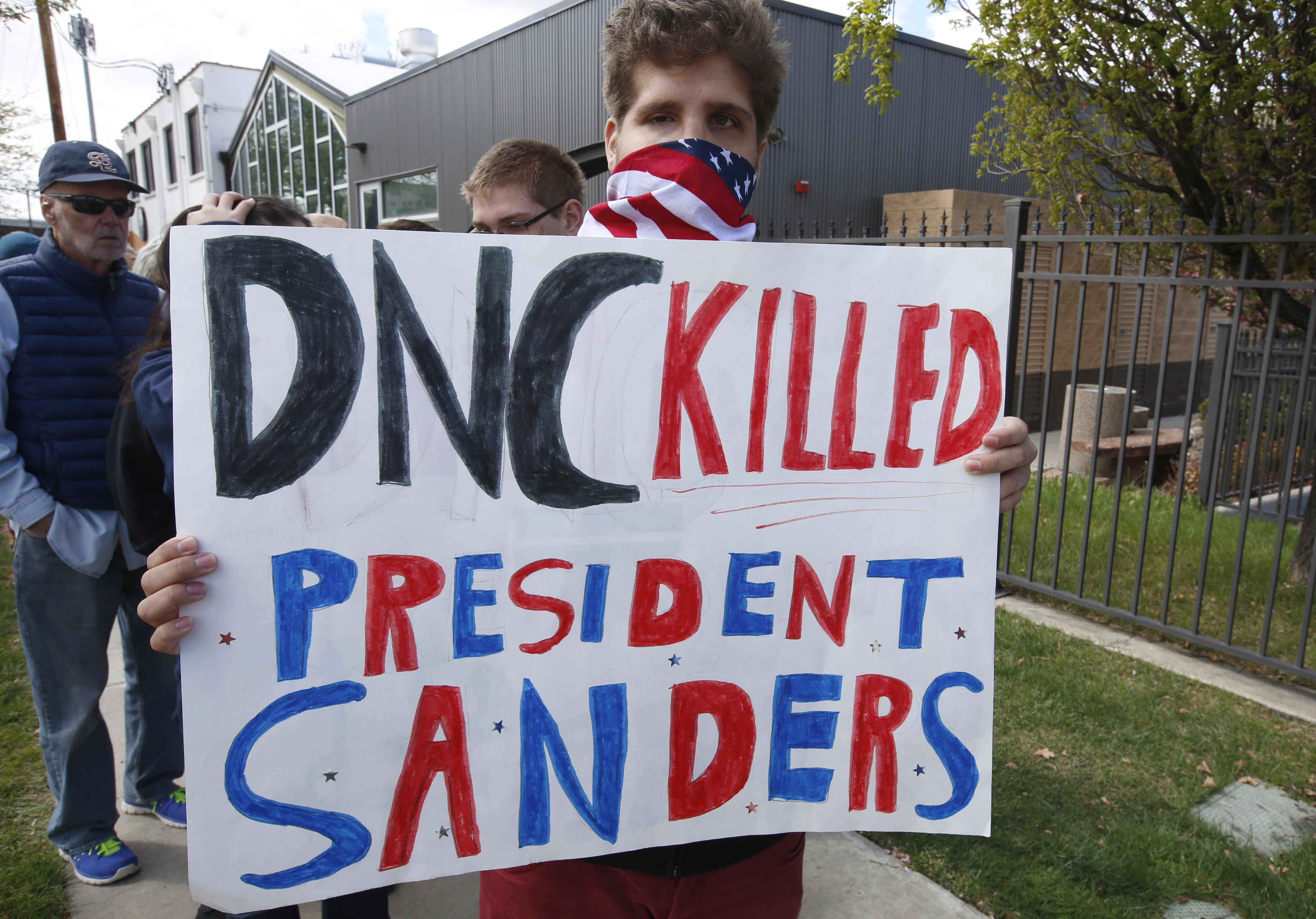 A man holds a sign reading “The DNC killed President Sanders” as he waits in line to enter aDemocratic unity rally with Bernie Sanders and DNC Chairman Tom Perez on April 21, 2017 in Salt Lake City, Utah.