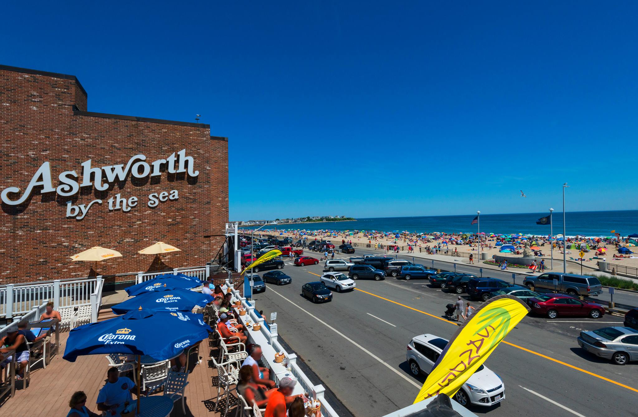Large lettering on a brick building reads Ashworth by the Sea. A road passes by, and there’s a beach on the other side.