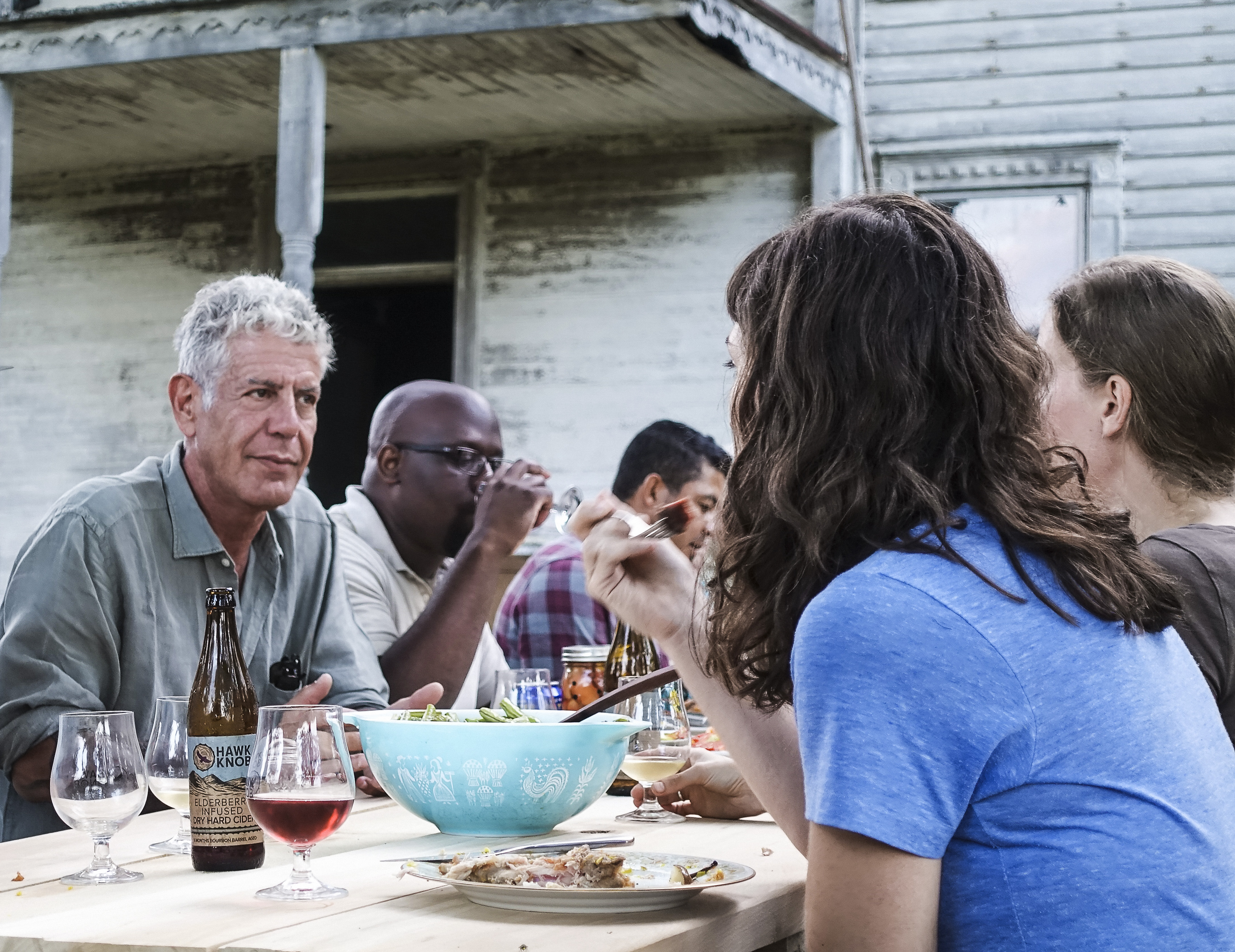 Anthony Bourdain sitting at an outdoor table in a scene from Parts Unknown: West Virginia.