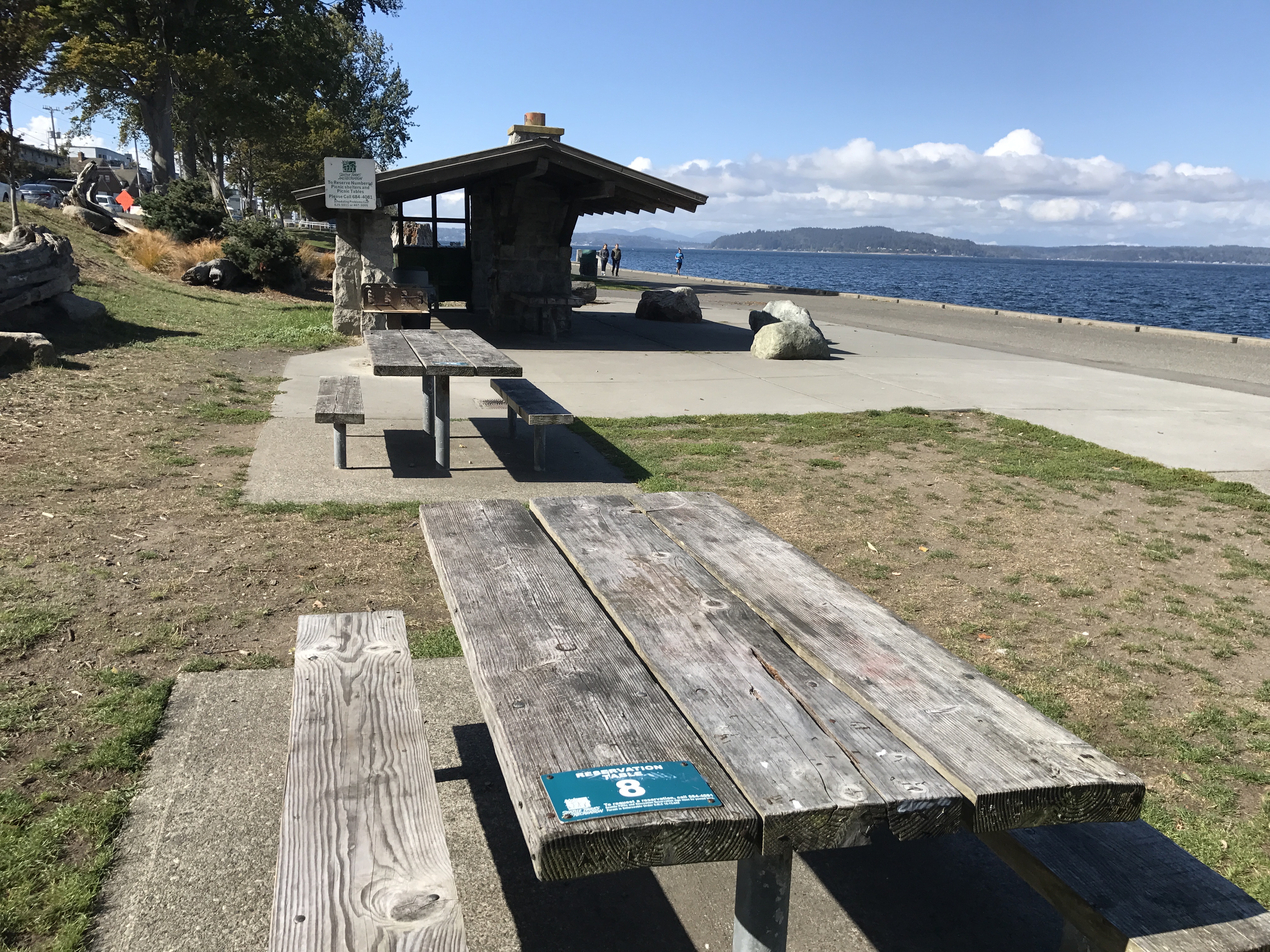 Two picnic tables and a picnic shelter along a beach.