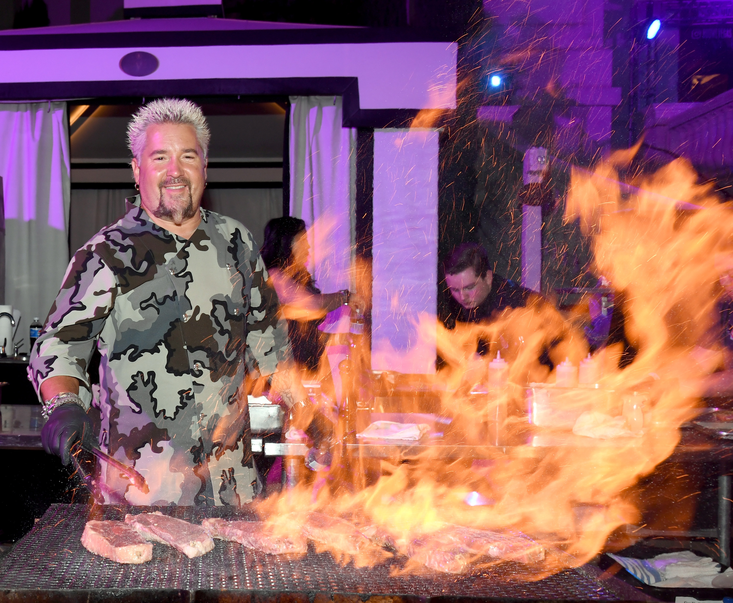 Guy Fieri grilling over a large fire