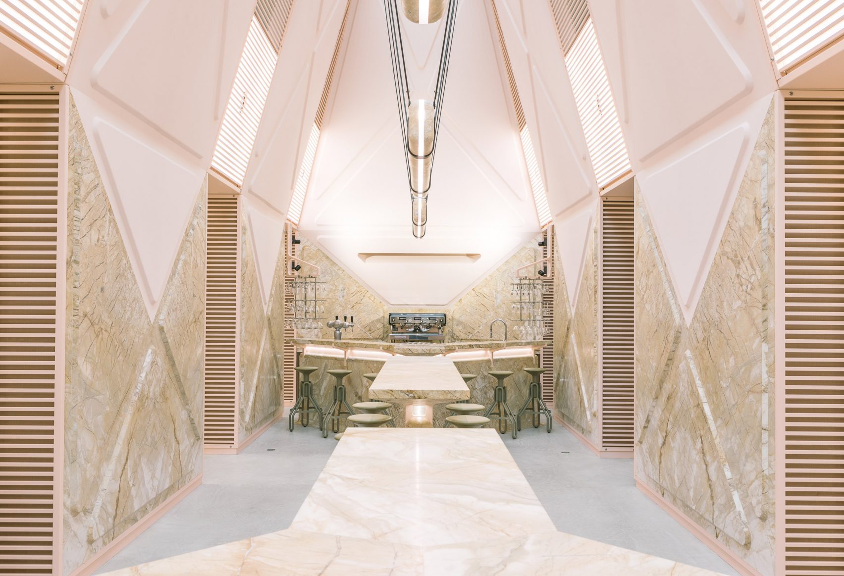 This lounge in Belgium is clad head to toe in pink marble, with a design that makes it look pulled straight from a science fiction film. The central space has a soaring ceiling and a pair of communal bars with soft rounded edges, while two rooms sit adjac
