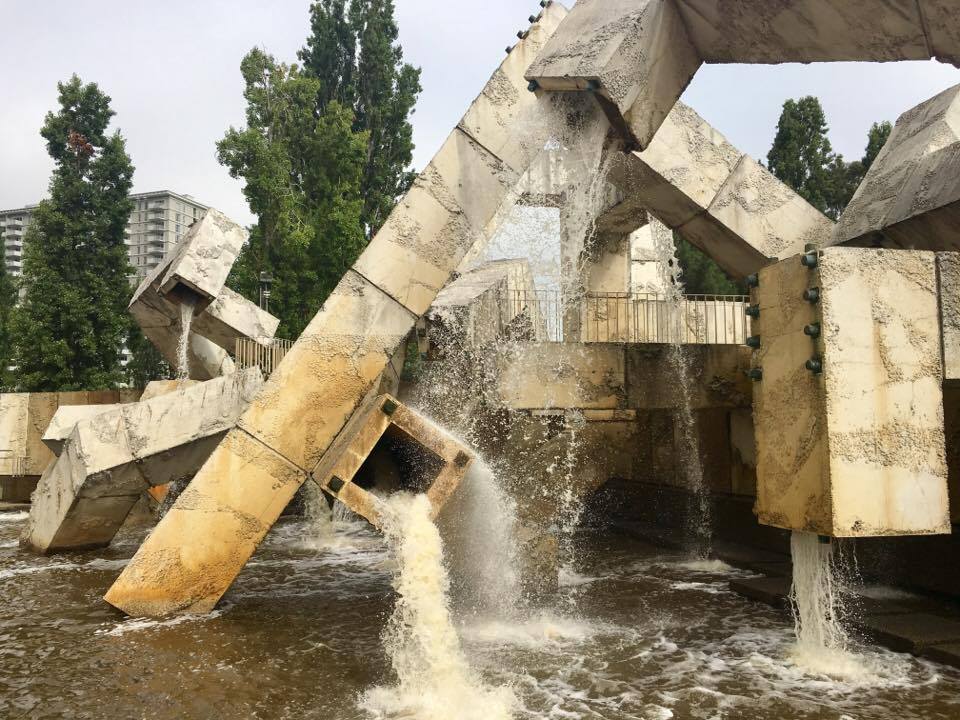 Brutalist fountain, boxy, concrete, running with water.