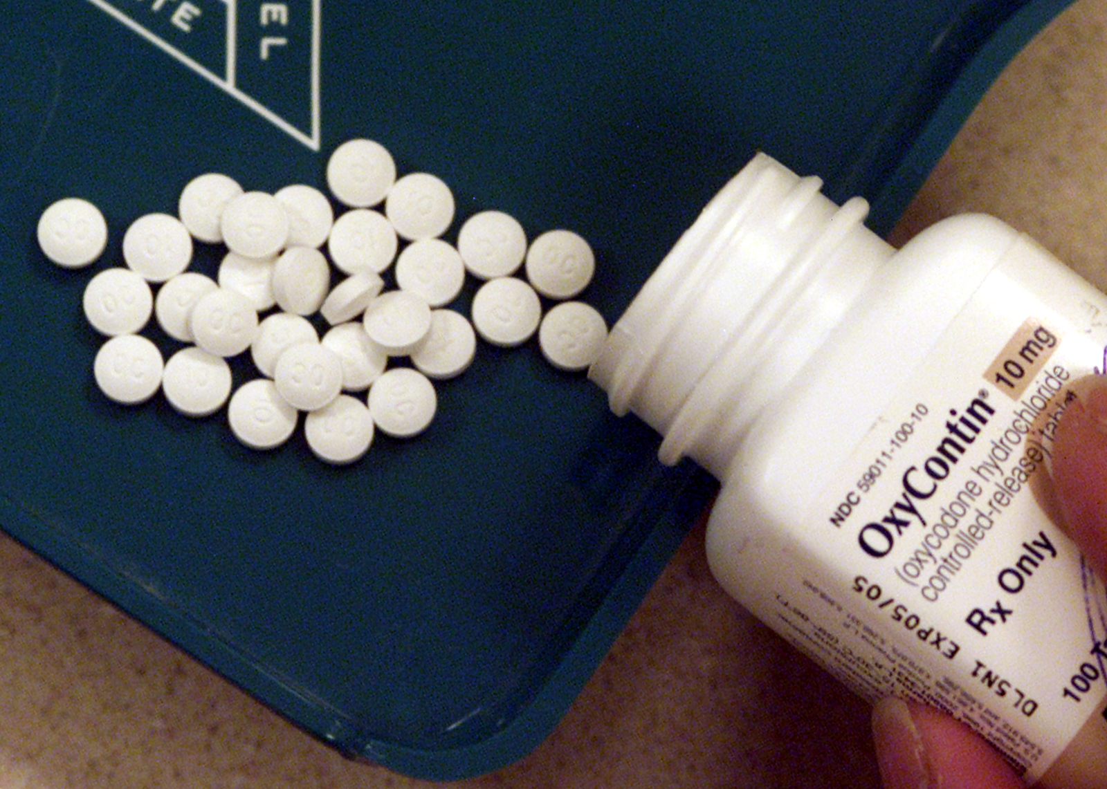 A bottle of OxyContin spilling opioid painkiller pills onto a countertop.