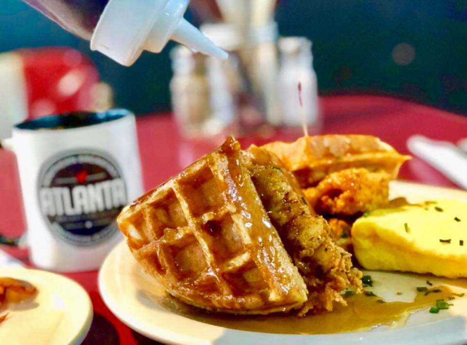 Fried chicken and two triangles of waffles covered in syrup with a folded egg and cup of coffee from Atlanta Breakfast Club.