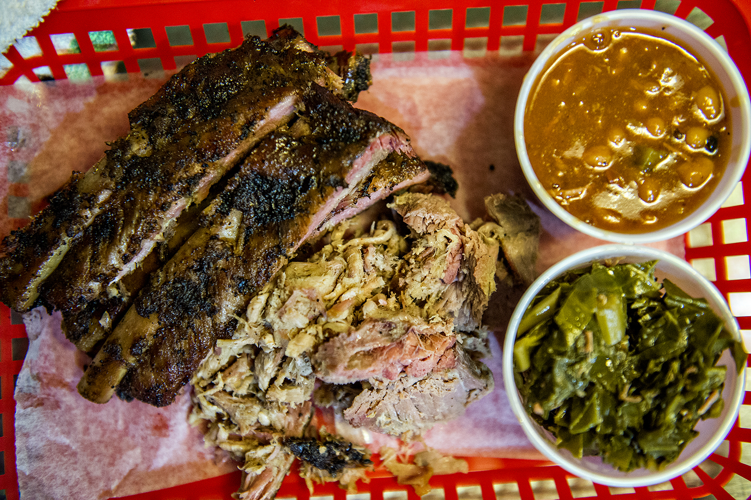A plate of ribs, chopped whole hog, barbecue beans, and greens.