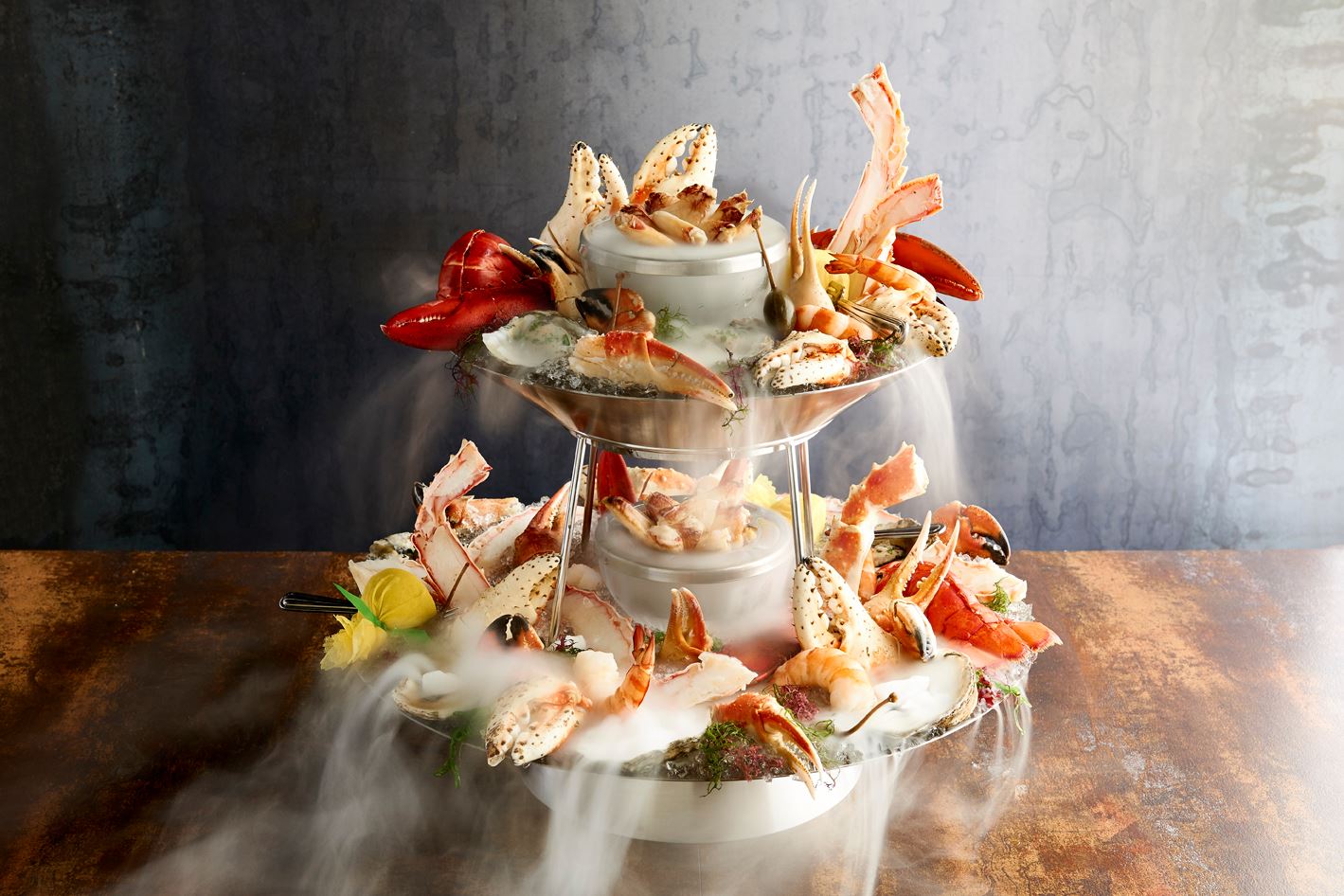Glamour shot of a multi-tier seafood tower, garnished with plenty of crab claws and dry ice