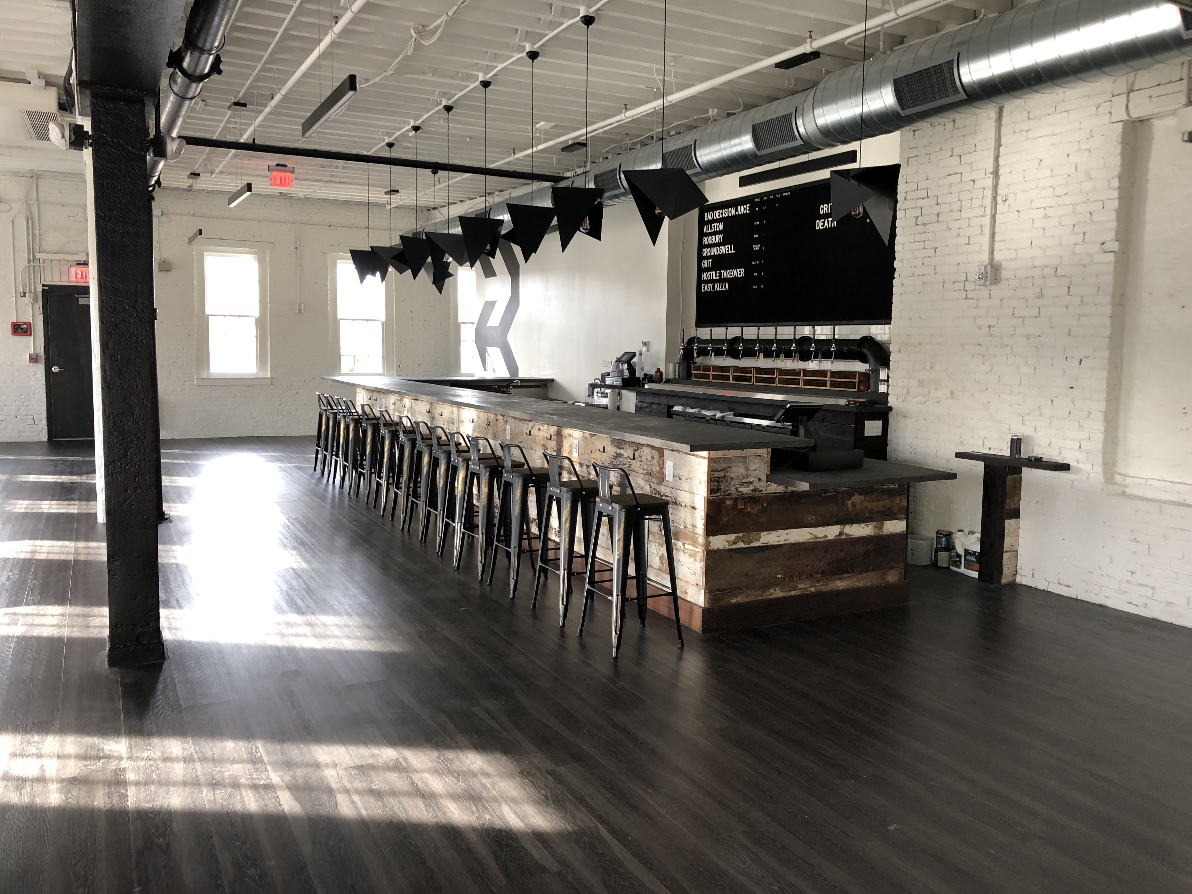 A spacious taproom built out in a former mill space, with white walls, one load-bearing beam, and a sparse, modern bar.