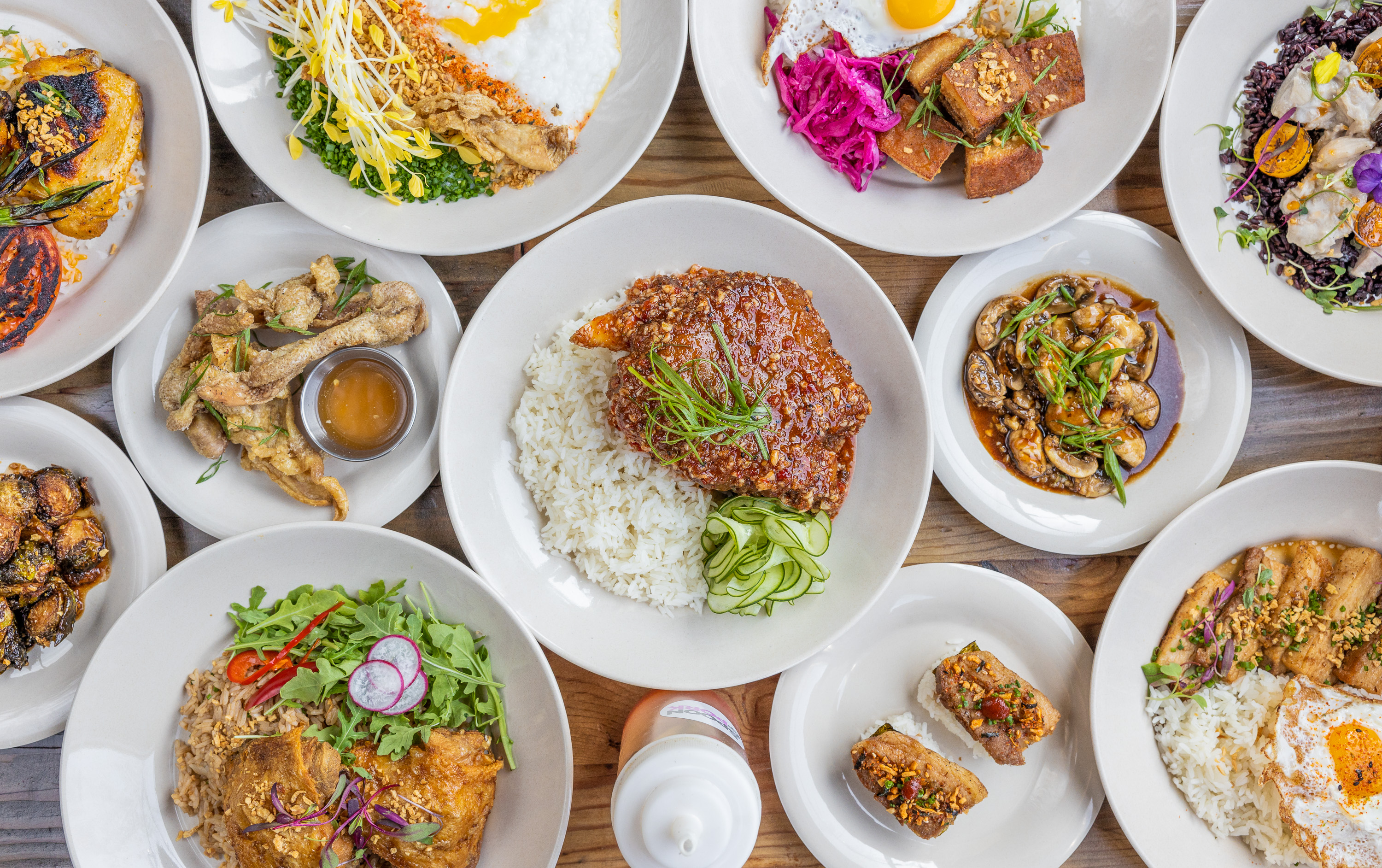 An overhead shot of Filipino food shared in round white bowls.