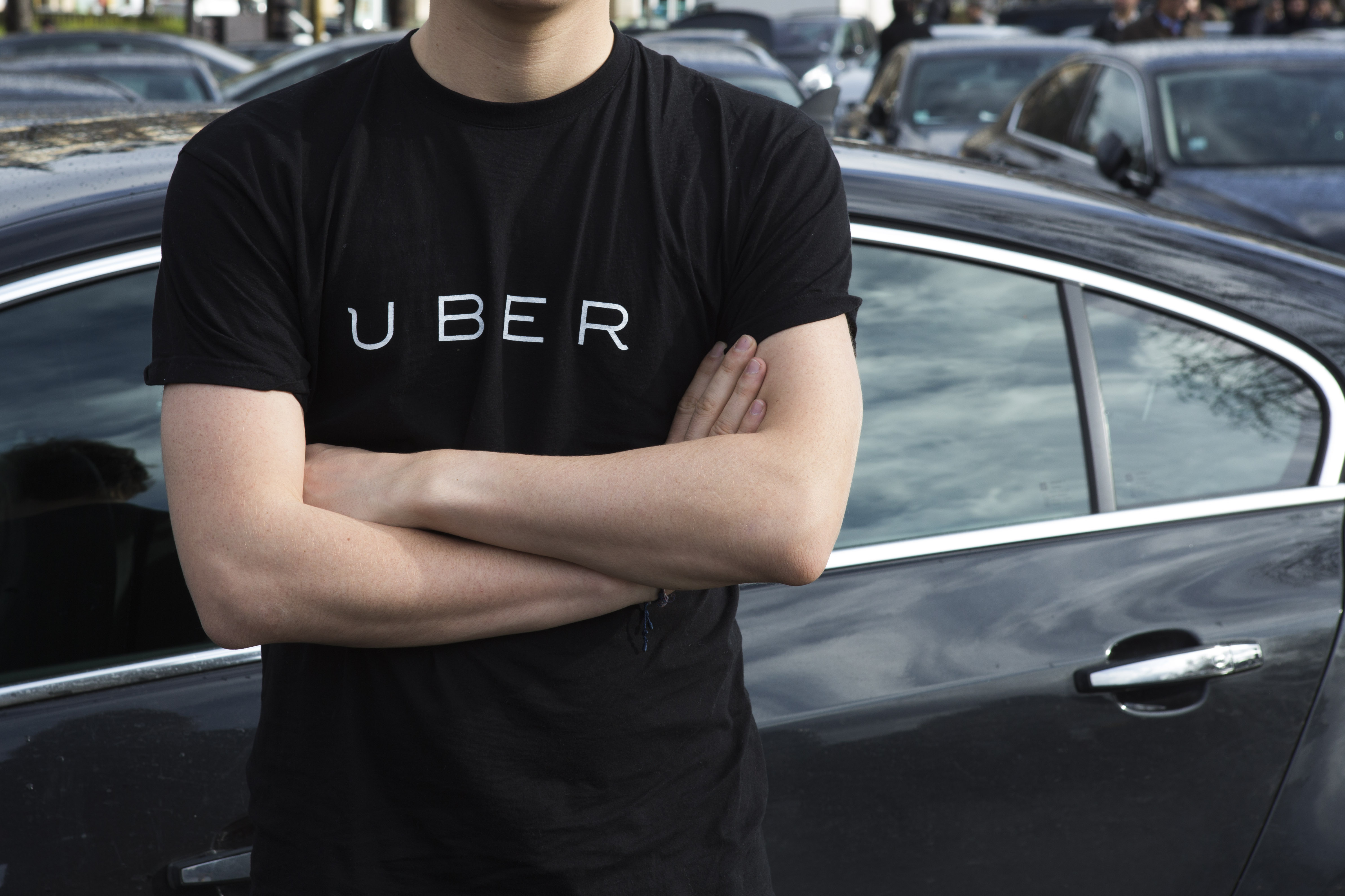 Uber driver in an Uber shirt in front of a black car