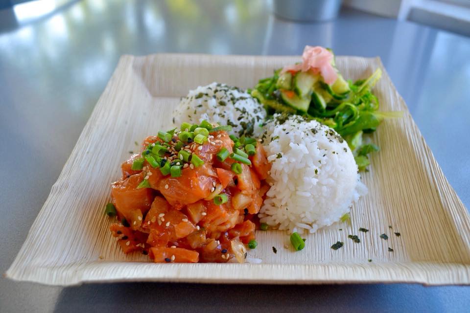 A pile of marinated poke next to a scoop of rice on a cardboard tray.