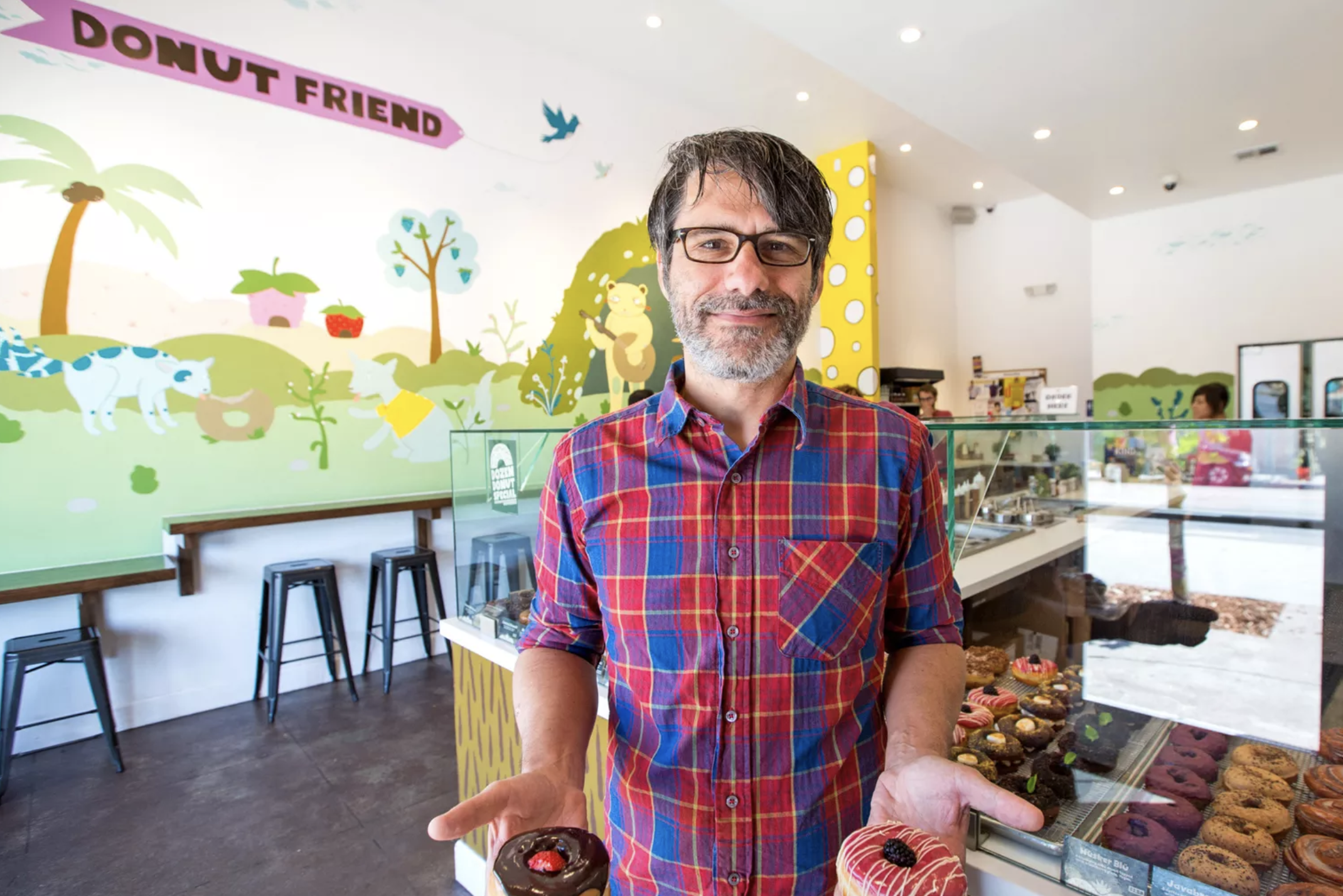 Donut Friend Mark Trombino holds a doughnut in each hand.