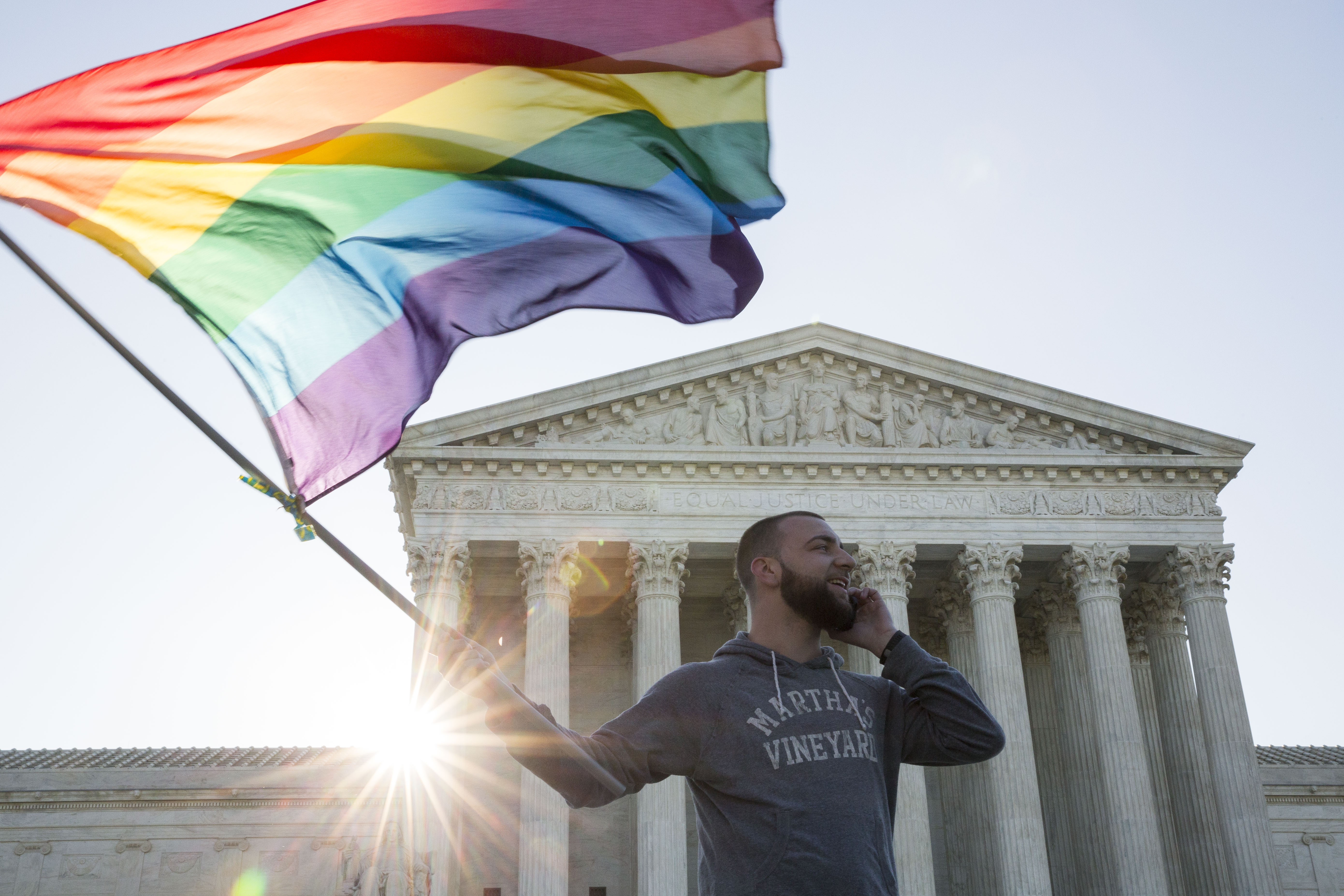 A marriage equality supporter waves a Pride flag in front of the US Supreme Court.