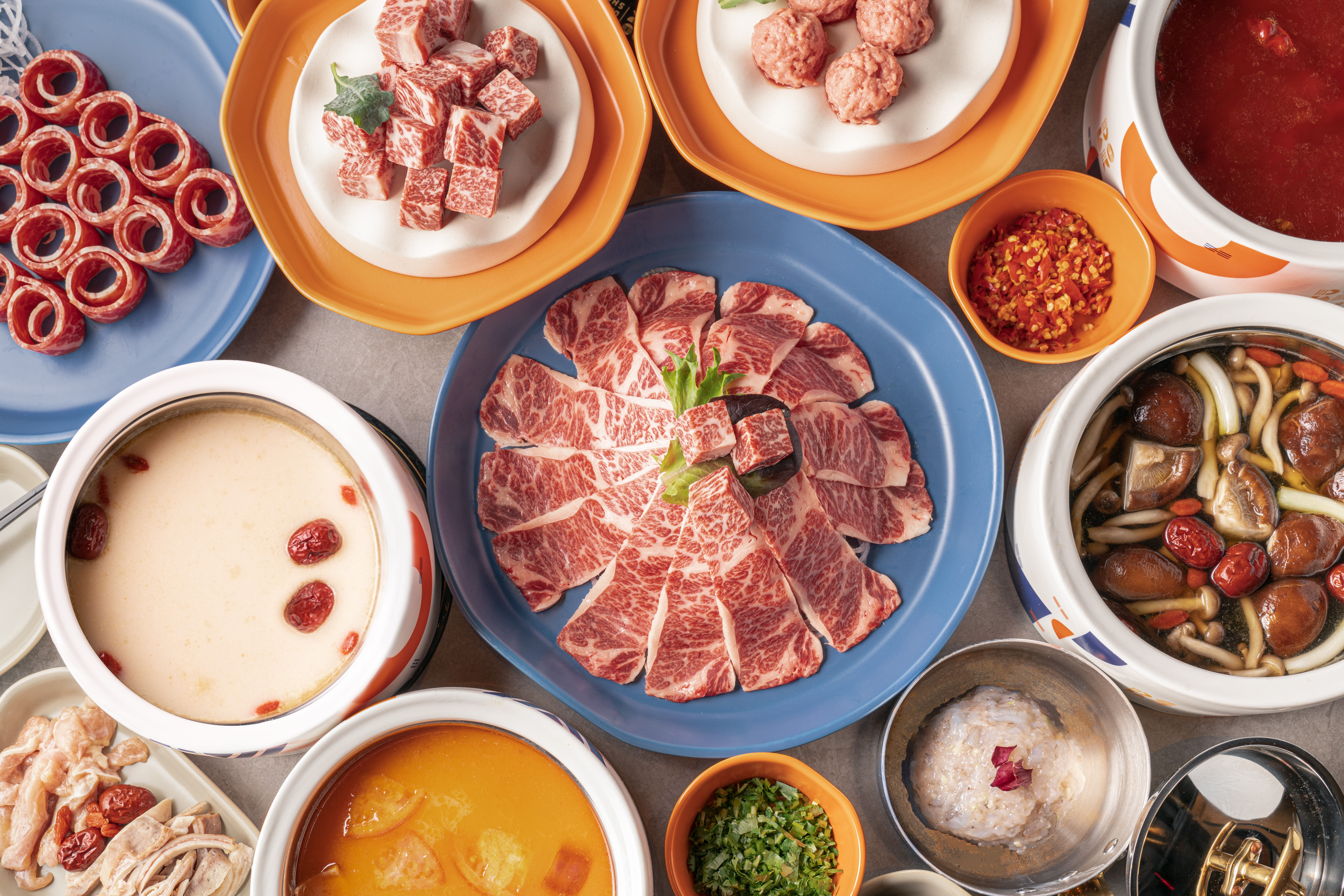 A hot pot spread at the Dolar Shop full of meats and broths.