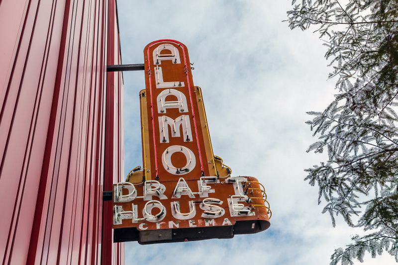 neon theater sign with blade that says Alamo Drafthouse