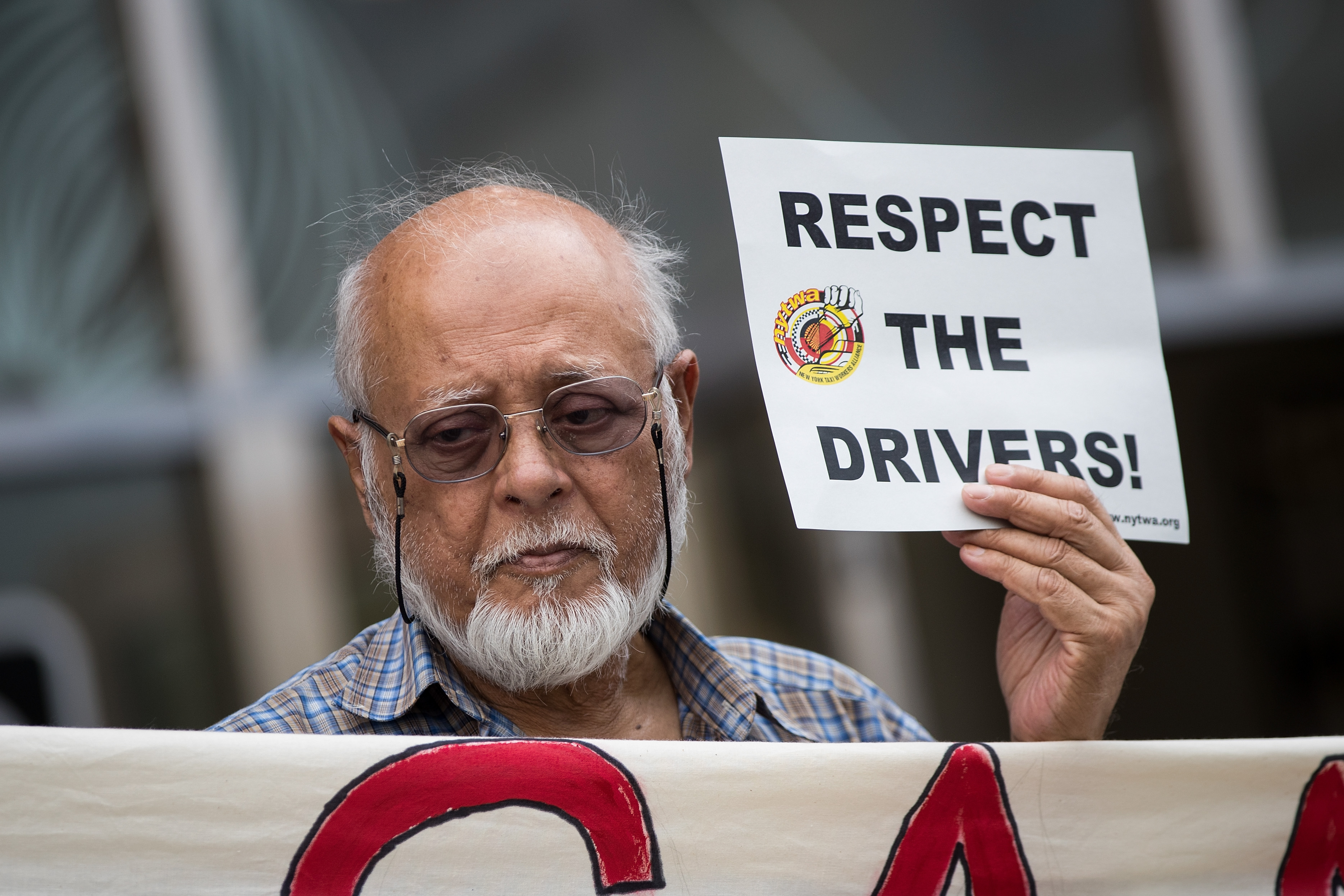 An Uber driver at a protest holds a sign reading, “Respect the drivers.”