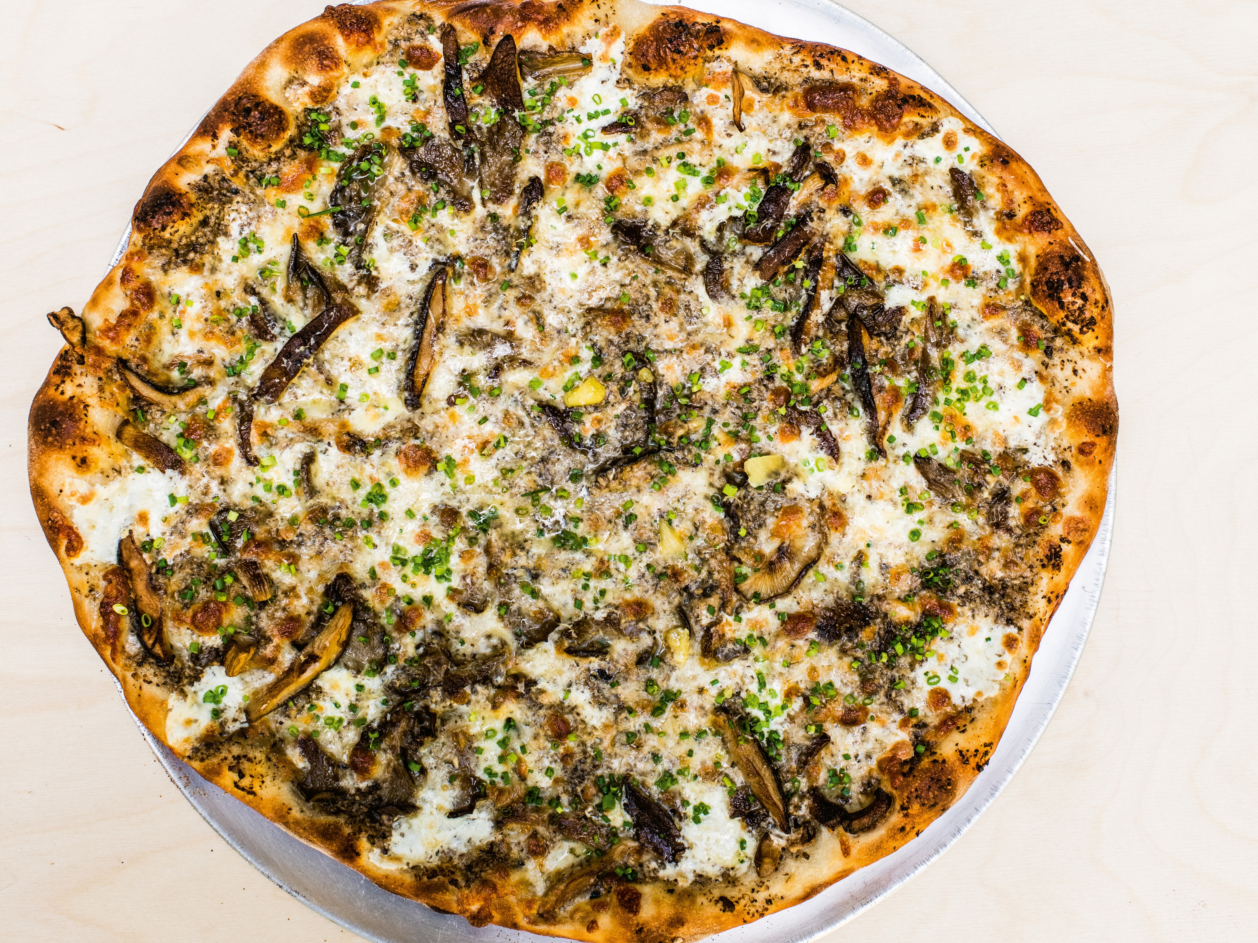 round pizza with mushrooms, scallions, and cheese