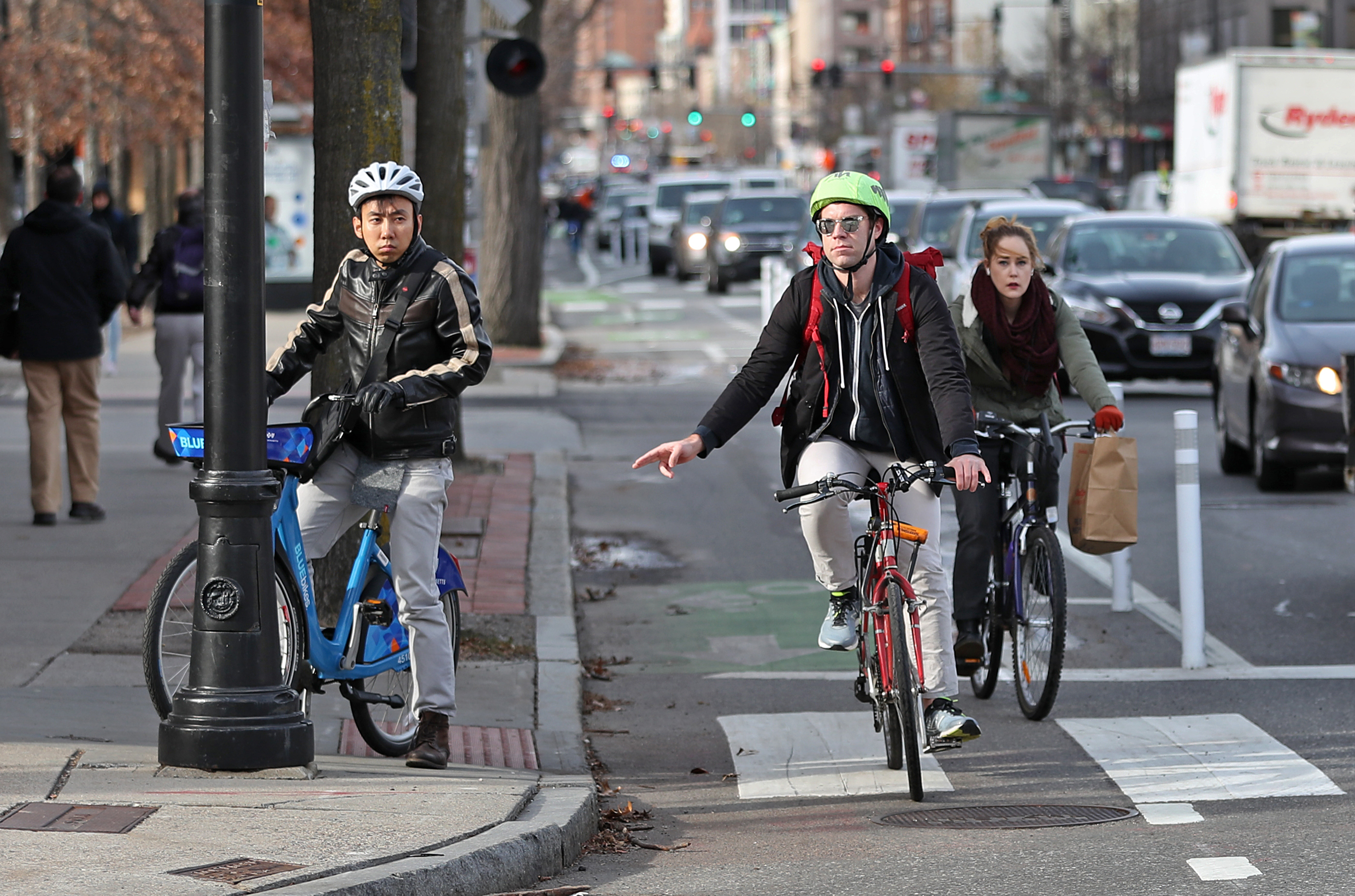 Three bikers rounding a corner in a protected bike lane. 
