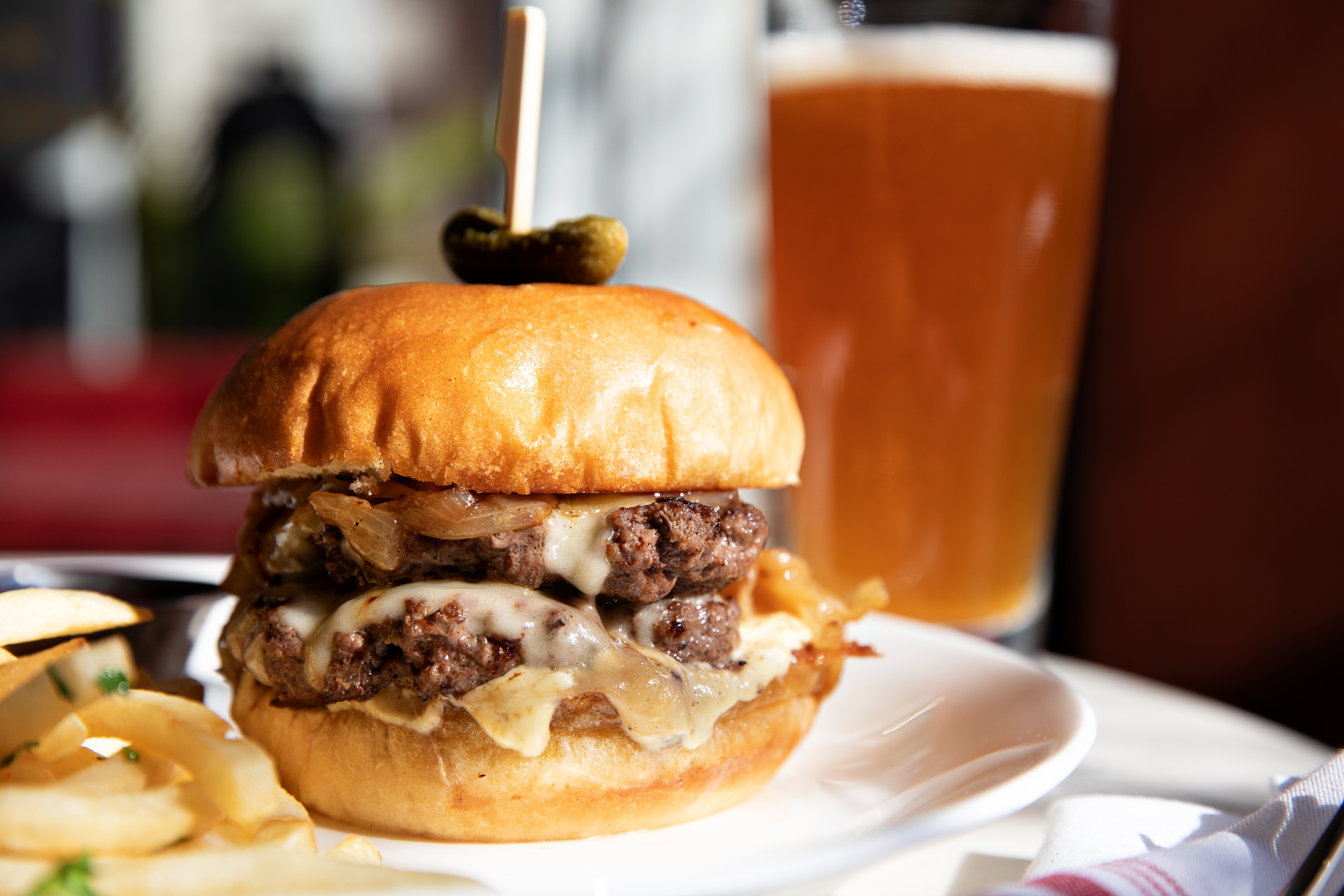 A double patty cheeseburger in front of a beer. 