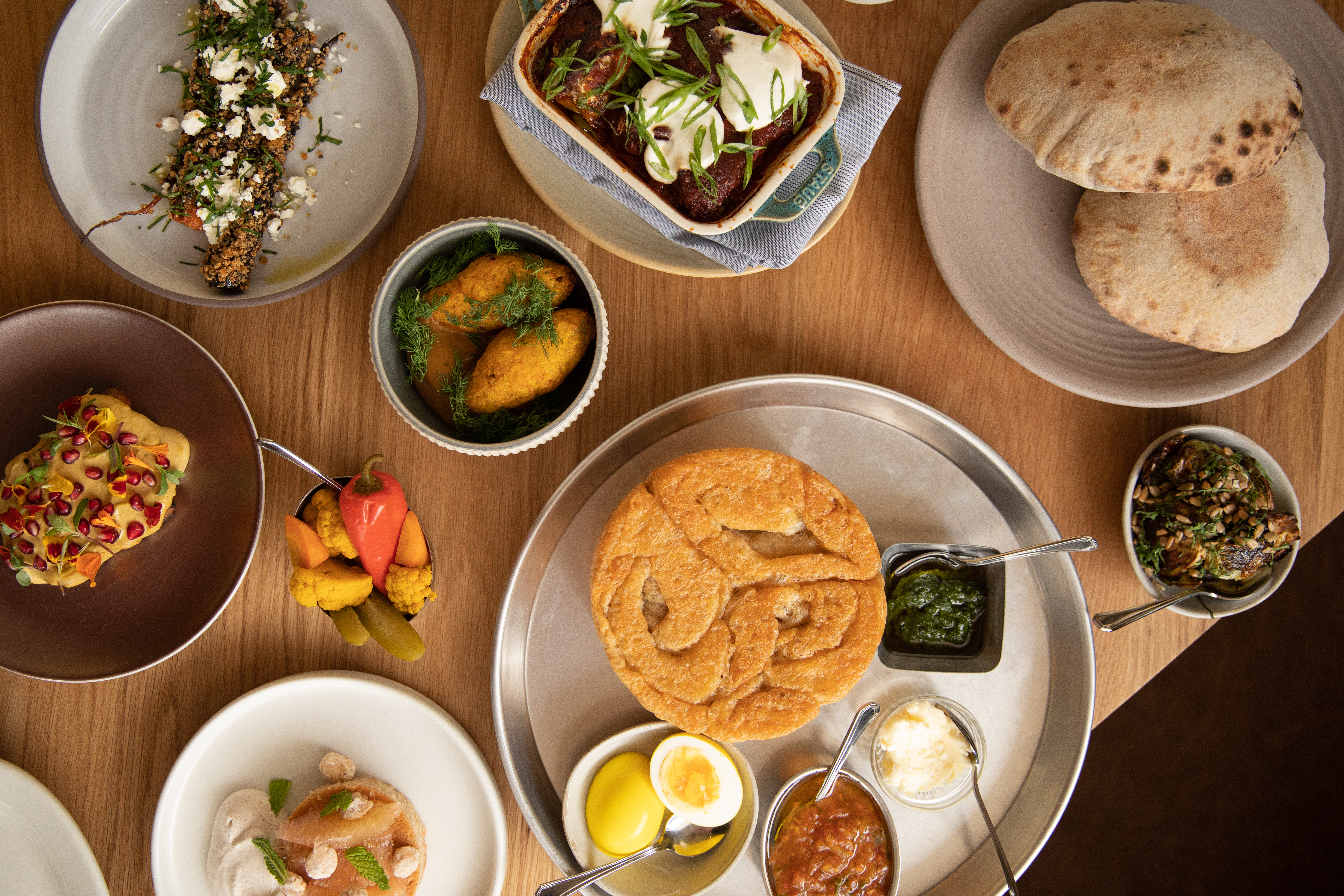 A spread of Galit’s Middle Eastern dishes includes breads, toasts, hummus, pitas, charred vegetables, and more.