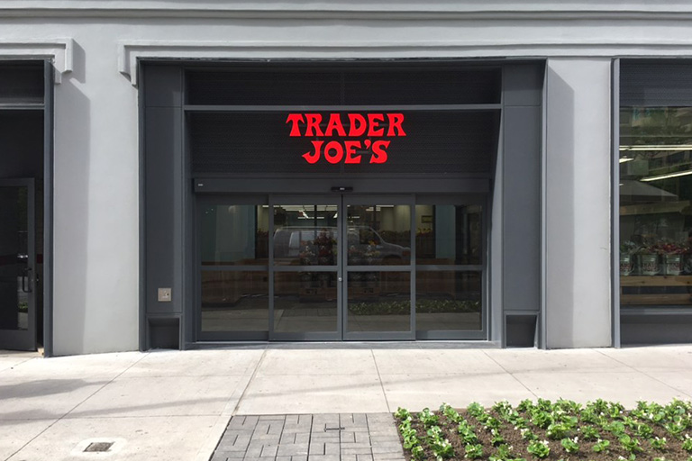 The exterior of a store with the words trader joe’s emblazoned in red